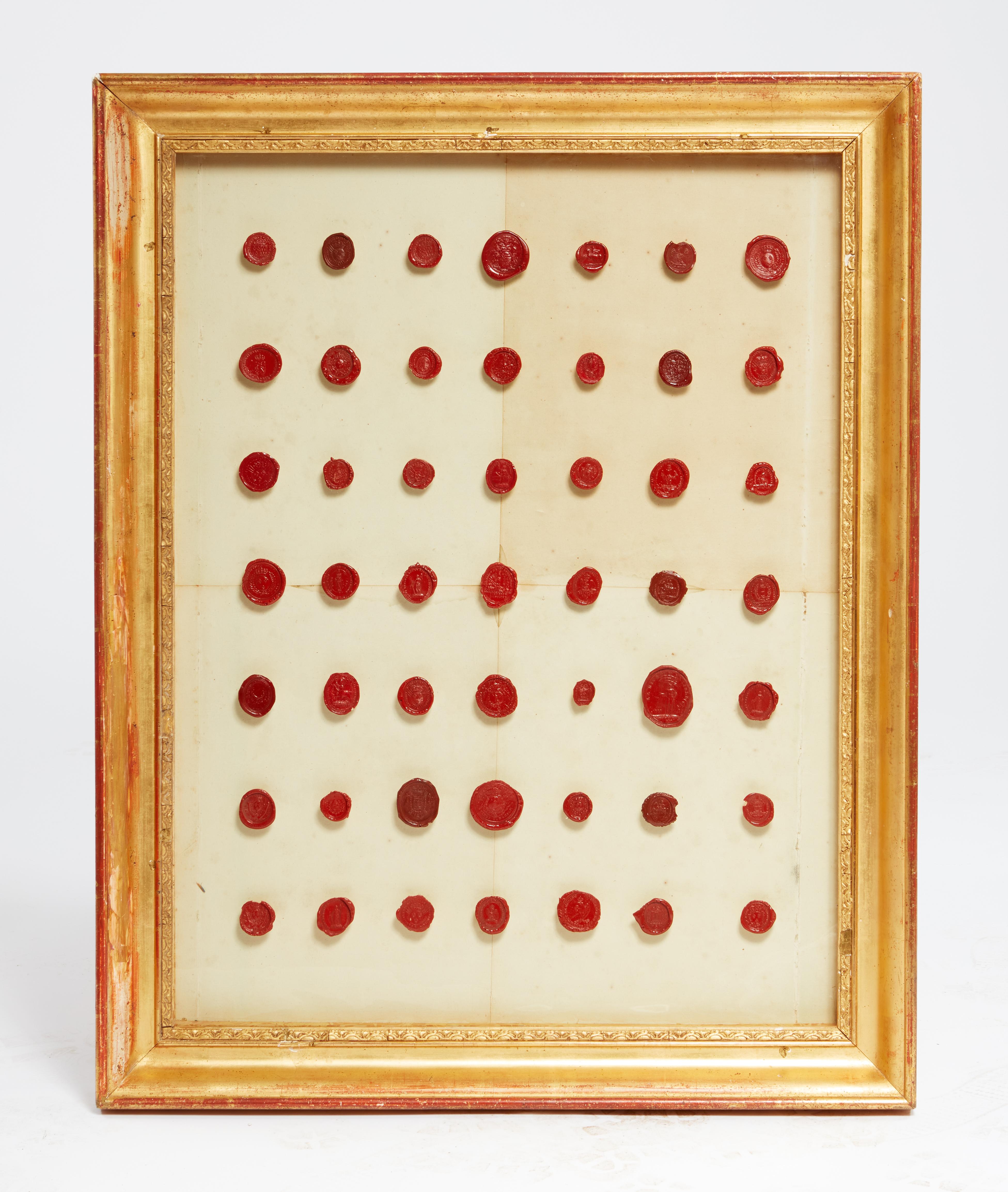 Incorniciata in legno dorato, la collezione di sigilli in cera rossa risale alla fine del XVIII e all'inizio del XIX secolo. Ogni sigillo viene montato su un perno di Wood e poi il gruppo viene montato su carta.  

NOTA: 
DIMENSIONI DEI QUADRI: 2