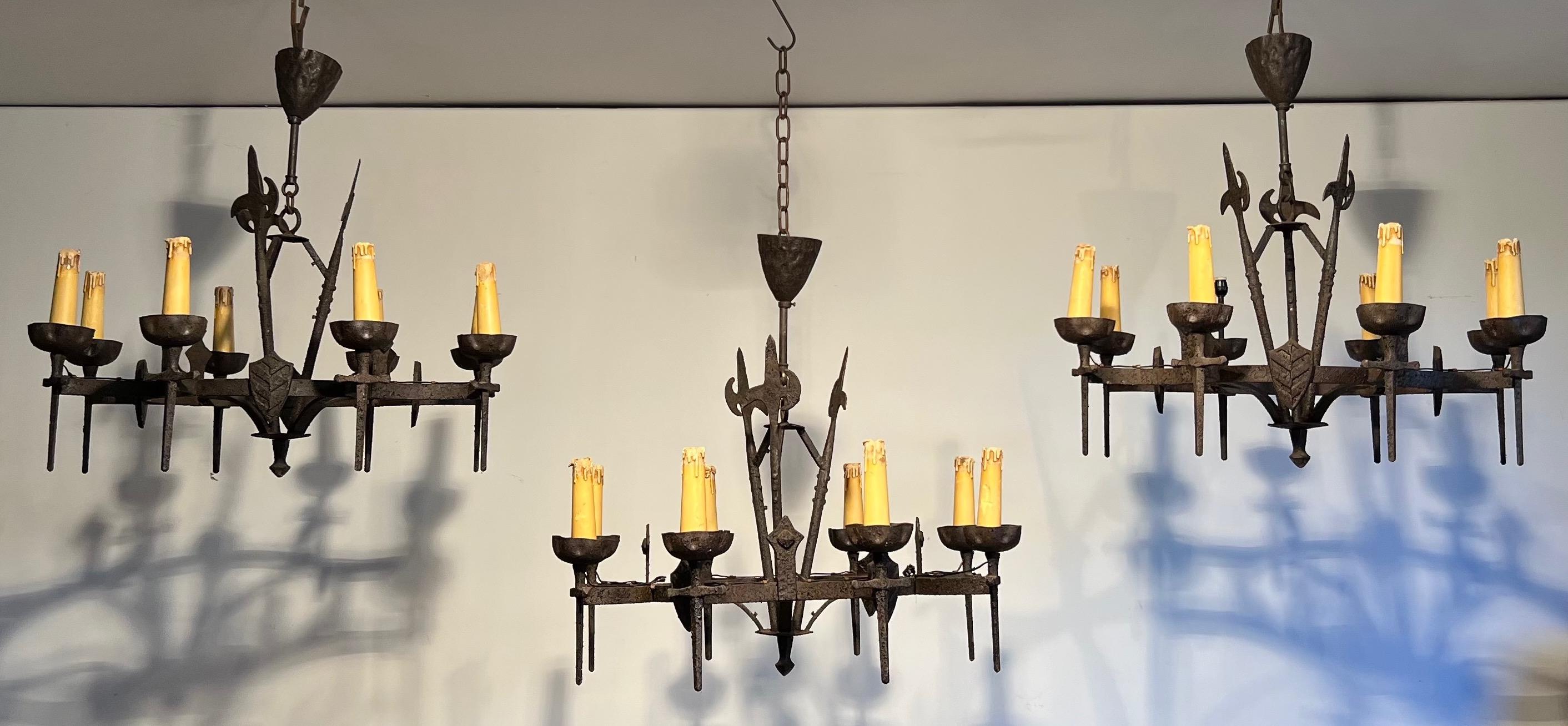This is a rare set of three chandeliers. These chandeliers are made of wrought iron with 8 arms. They are in the Gothic style. Chandeliers can be sold individually. This is a French work. Circa 1950