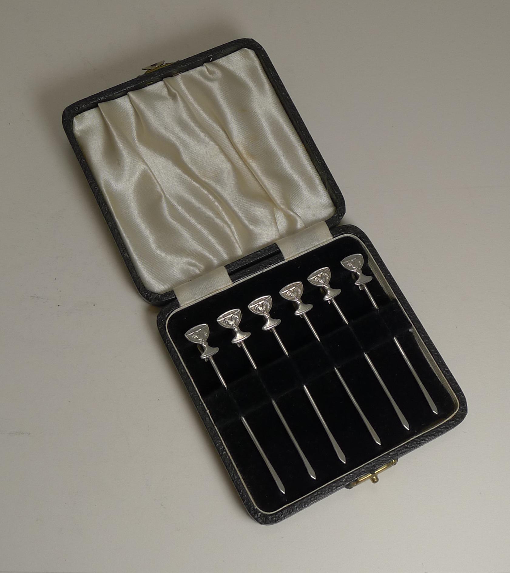 A fabulous and very unusual set of six cased sterling silver cocktail sticks each terminating with a Champagne coupe glass each with a cockerel or rooster to the centre. Each also has a hook to the back to attach to the glass rim.

They are