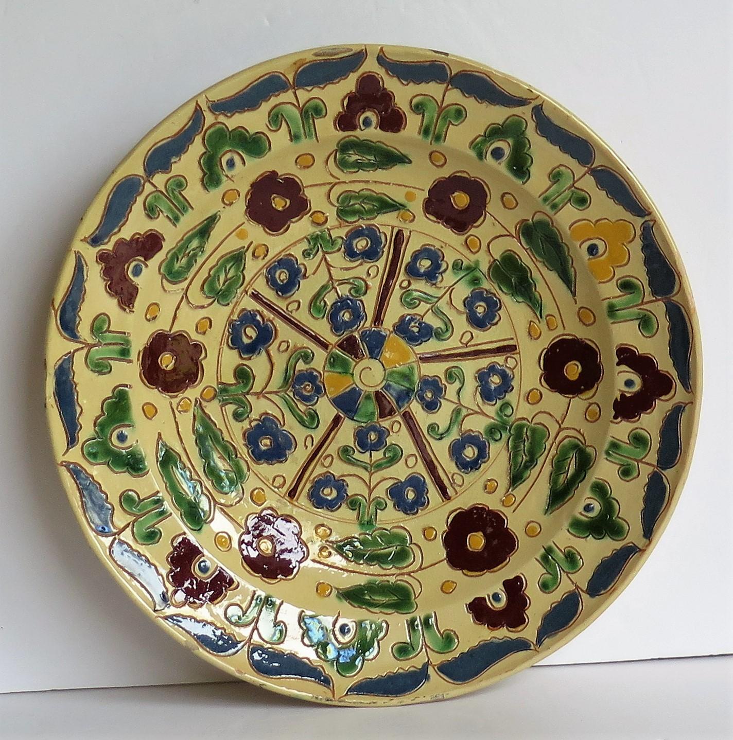 A large charger plate made of Redware pottery, all hand decorated in the Sgraffito Slip Decorated technique, with a stylized floral pattern. 

This is a large 11.75 inch diameter plate / charger or dish raised on a low foot. 

This bold pattern has