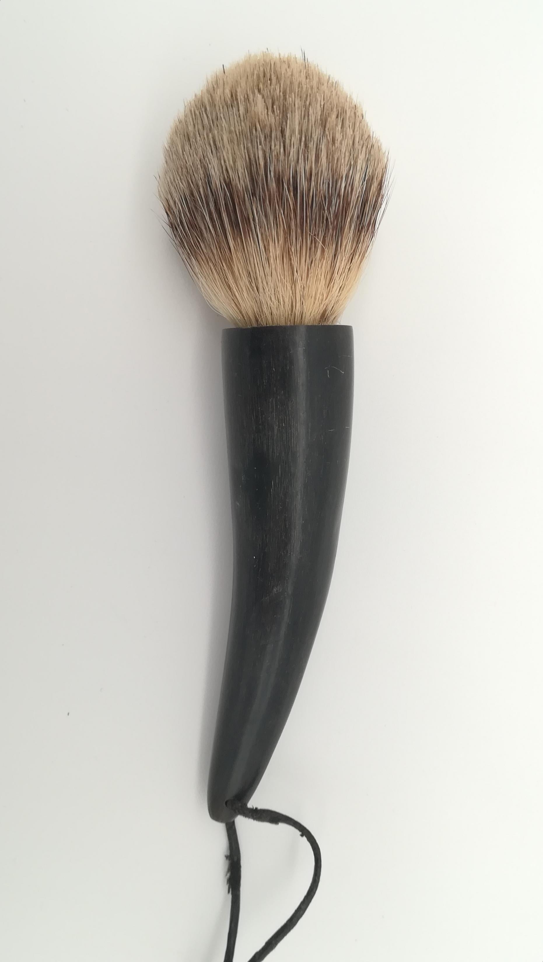 Organic water buffalo horn and badger hair shaving brush attributed to Carl Aubock. With original leather ribbon to hang it. Looks like never used. Rare Gentelmans accessory.