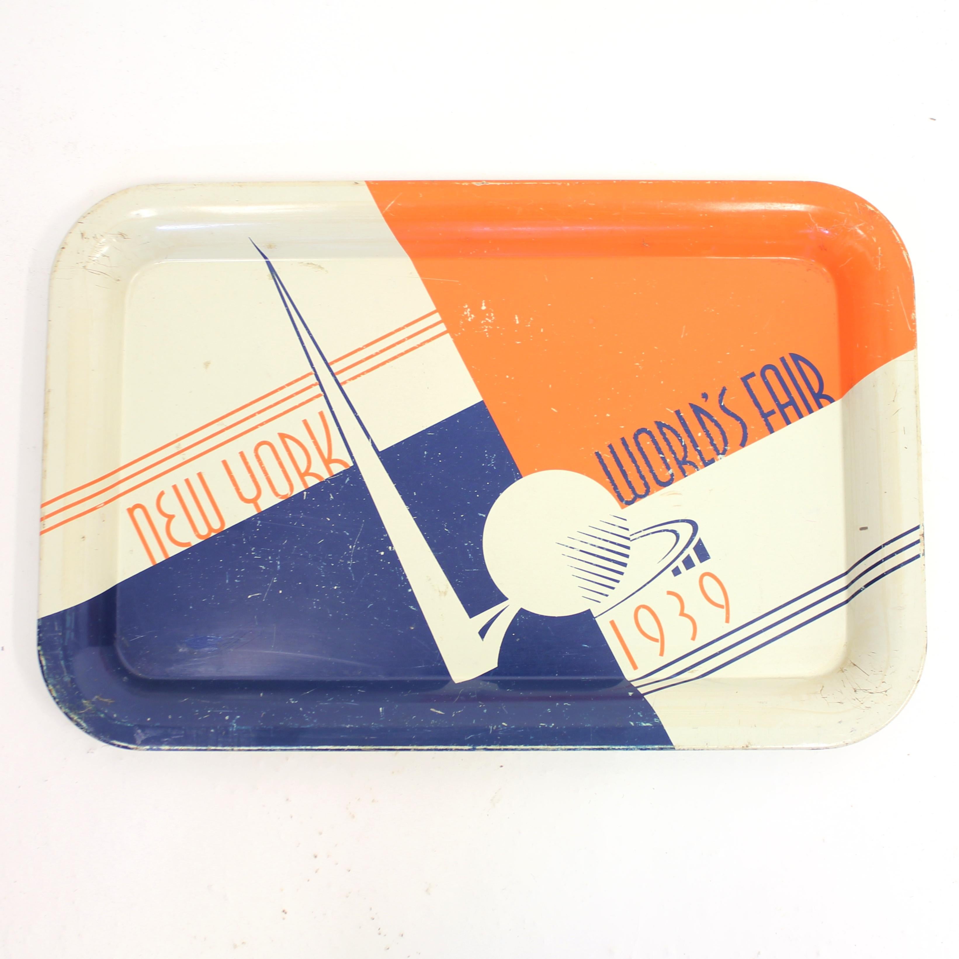 Rare Art Deco sheet metal tray in dark blue, orange and cream white from the very famous New York World's Fair 1939. The front side with a few scratches and marks from normal use, backside with a bit of light rust and missing paint but over all in a