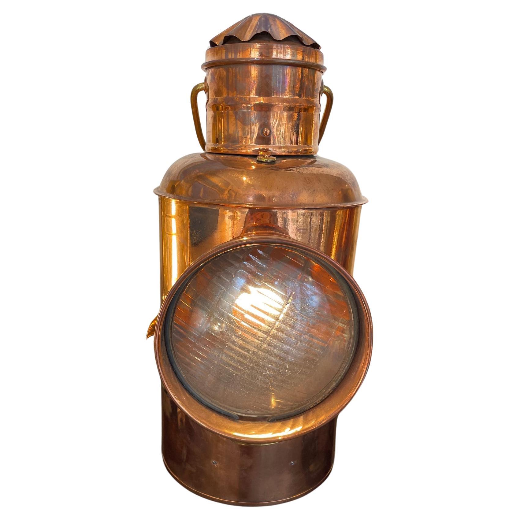 A rare ship's copper shutter signal light with a round Fresnel lens.  The shutter on the side is used for transmitting Morse Code.  The back has a door that gains access to the oil lamp and has a slide latch to stay closed.  We also had it converted