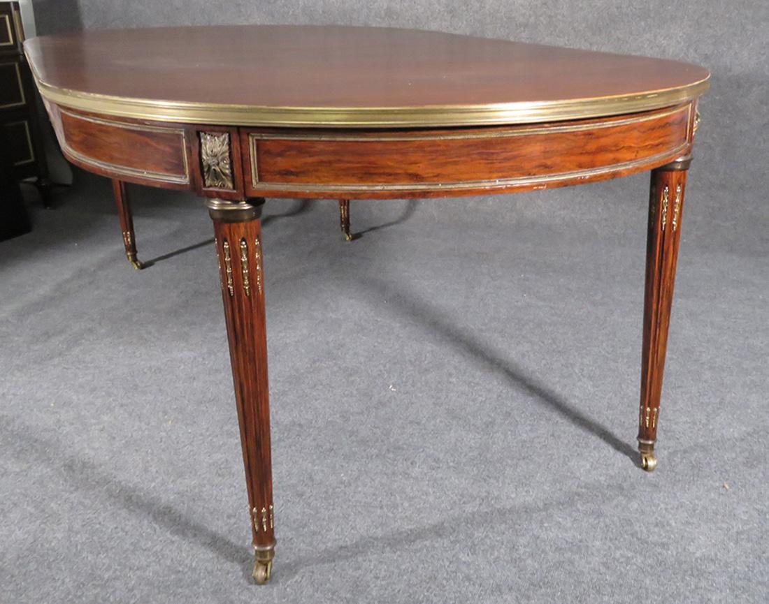 This is an outstanding and very rare form of Maison Jansen dining table. The table is made of rosewood instead of the usual mahogany and has beautifully varigated wood grain with the typical black and brown streaks that only rosewood shows so