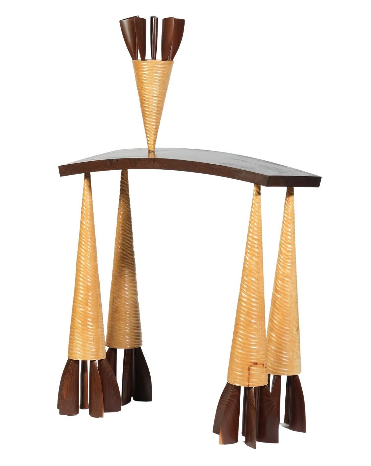 Wendell Castle, American (1932-2018). Unusual carved and lacquered wood console table raised on 4 triangular cone legs with a reverse curved top that has an attached inverted cone. Signed and dated on side of top, 1986.