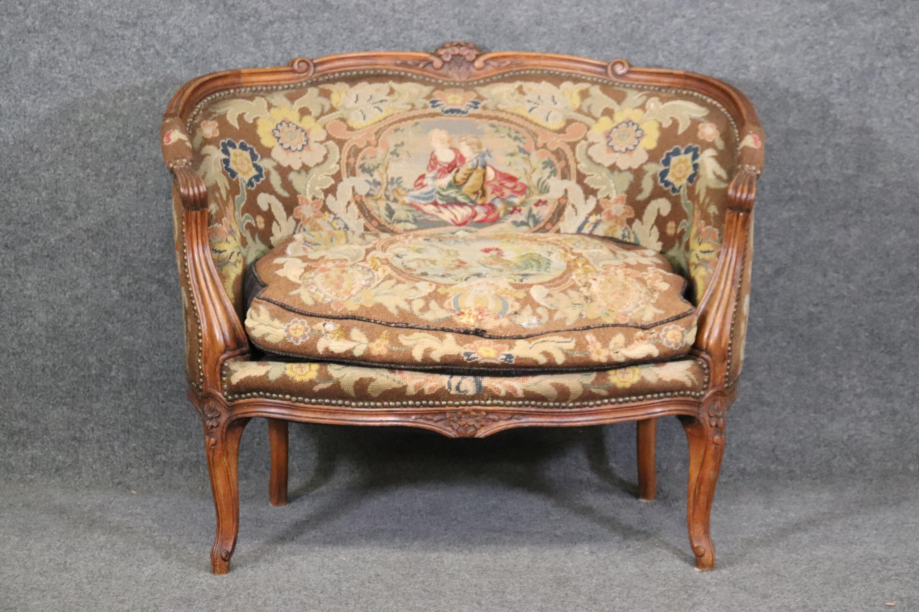 This is a charming needlepoint upholstered canape or marquis. The small size of 40.25 wide x 26.75 deep x 32.75 tall and a seat height of 20 inches makes it a wider chair, rather than a settee. The upholstery is original so expect small frays, wear