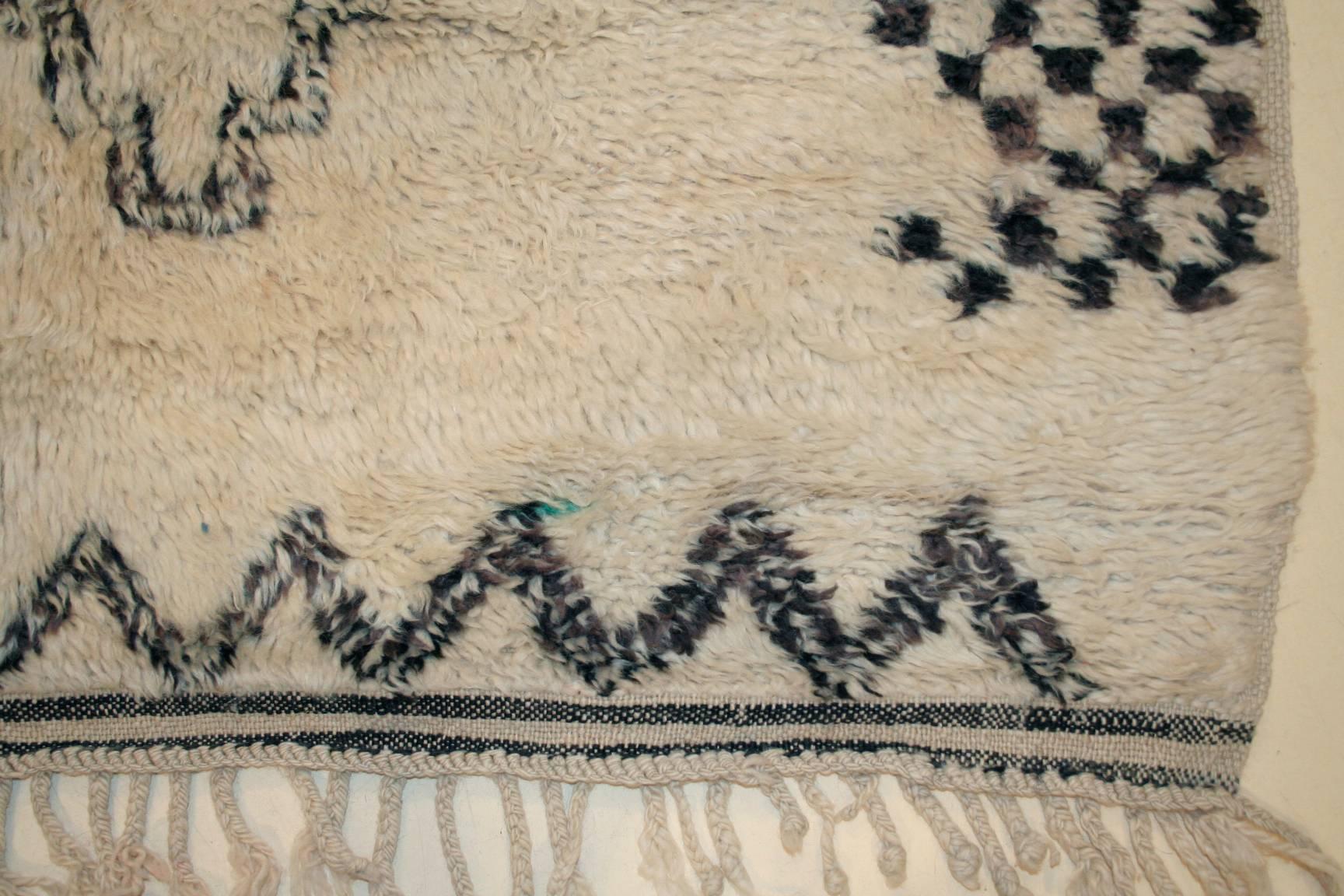 The rugs of the Beni Ouarain tribal confederacy, located in the northeastern portion of the Moroccan Middle Atlas, differ from other Berber weavings in that they are woven almost exclusively on an ivory background and decorated with abstract