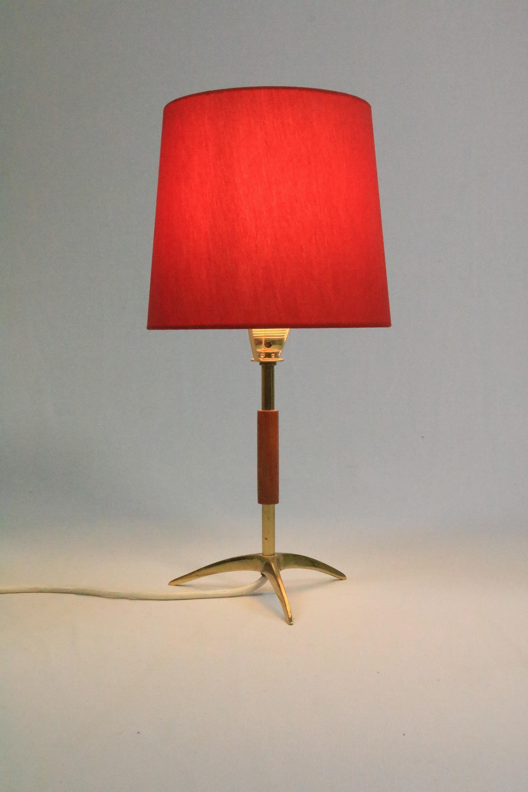 A very rare and beautiful table lamp  with teak and brass elements and crow's foot.
By Kalmar, Austria
Makes a wonderful light when on!

New professionally made lampshade in very harmonious matching red.
New brass socket, which is much more in