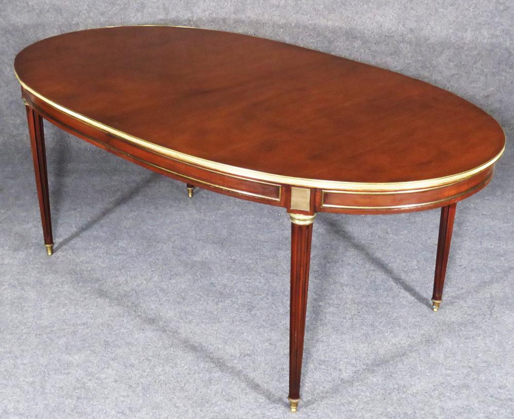 Measures: 42.5 wide x 72 wide x 29.5 tall. There are two 18 inch leaves for a total possible length of 108.

This is a gorgeous solid mahogany Maison Jansen brass trimmed Louis XVI dining table. Featuring the Classic lines of the finest of