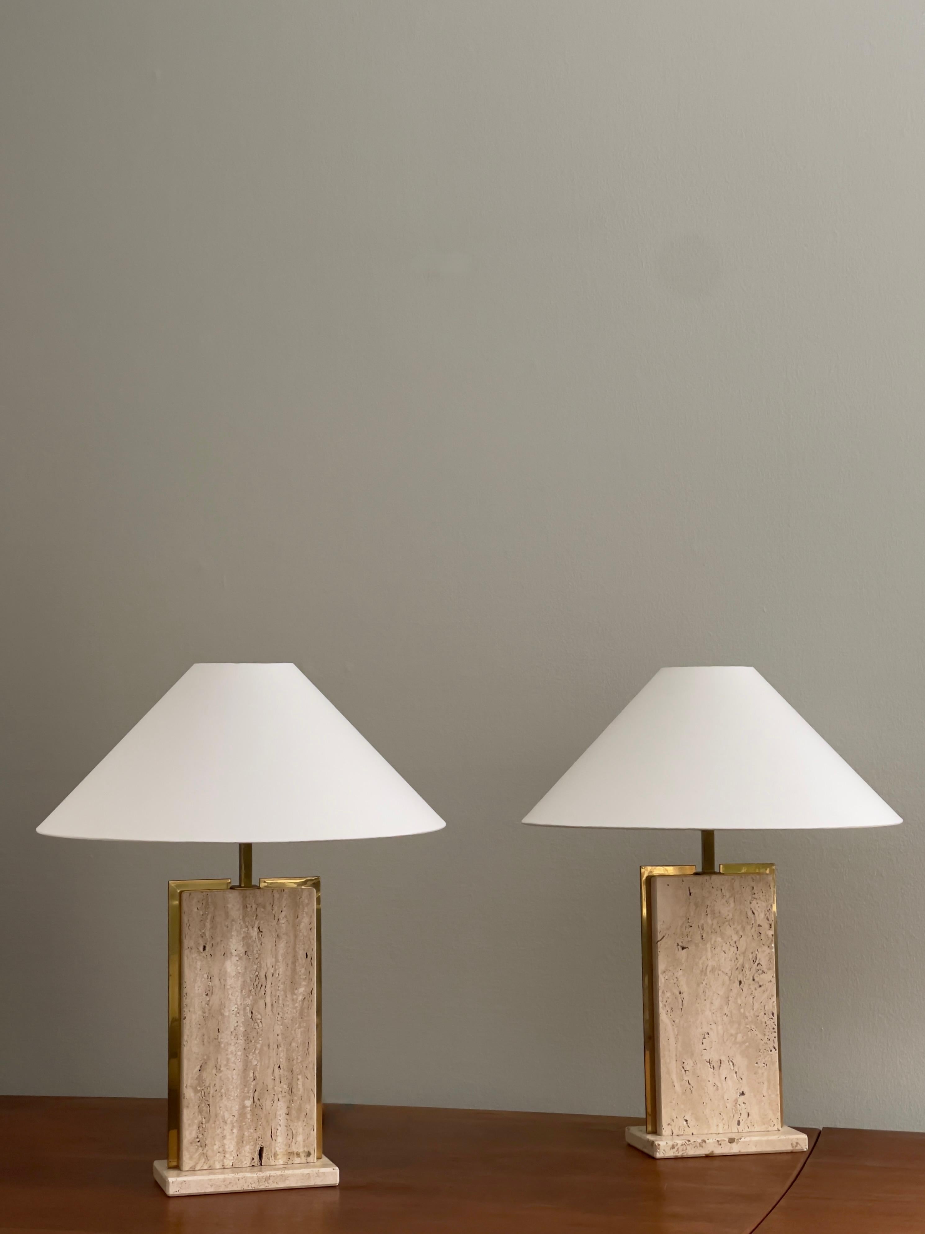 Questa rara e solida coppia di lampade da tavolo francesi degli anni '70 esemplifica l'eleganza minimalista e la raffinatezza dei materiali caratteristiche del design postmoderno. Realizzate in ottone e travertino, le lampade presentano una forte