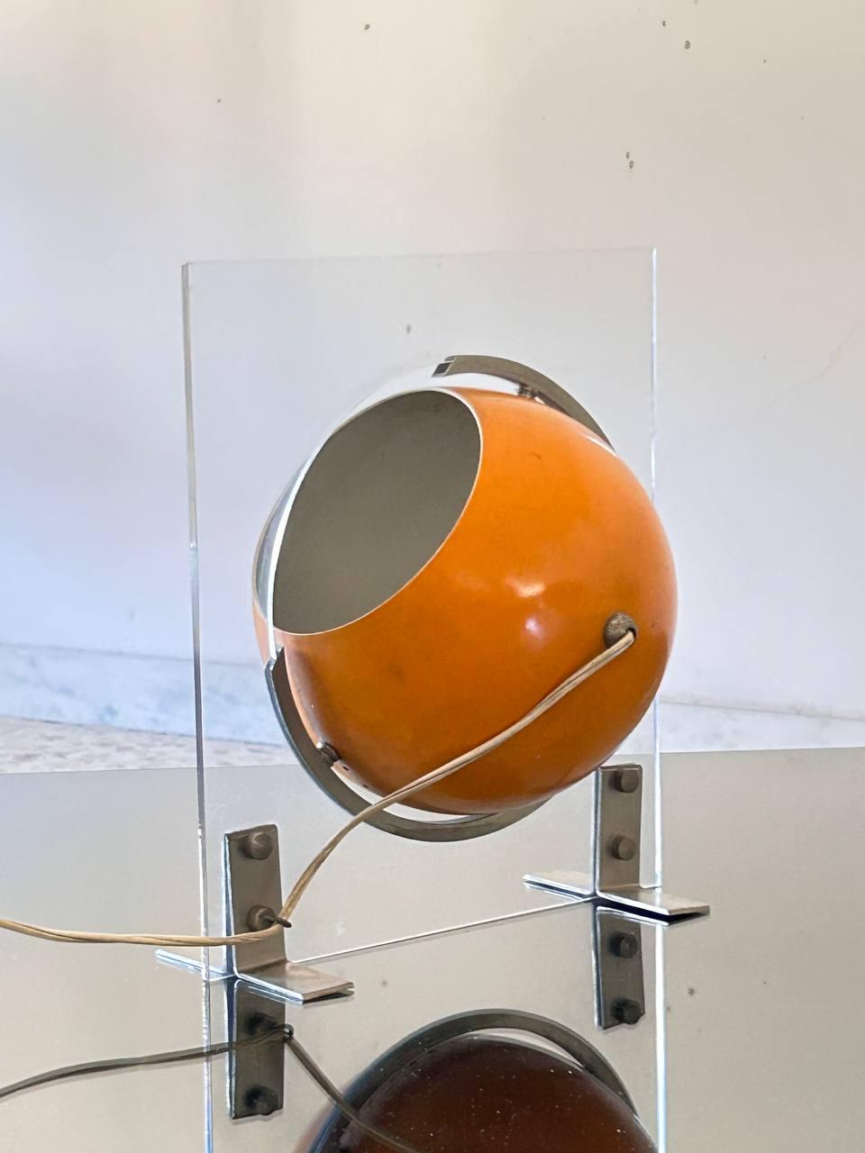 Rare lampe de table attribuée à Jean Dudon, composée d'une feuille de lucite qui non seulement réfracte la lumière, créant une lueur intéressante lorsqu'elle est allumée, mais agit également comme un rail sur lequel la calotte métallique peut