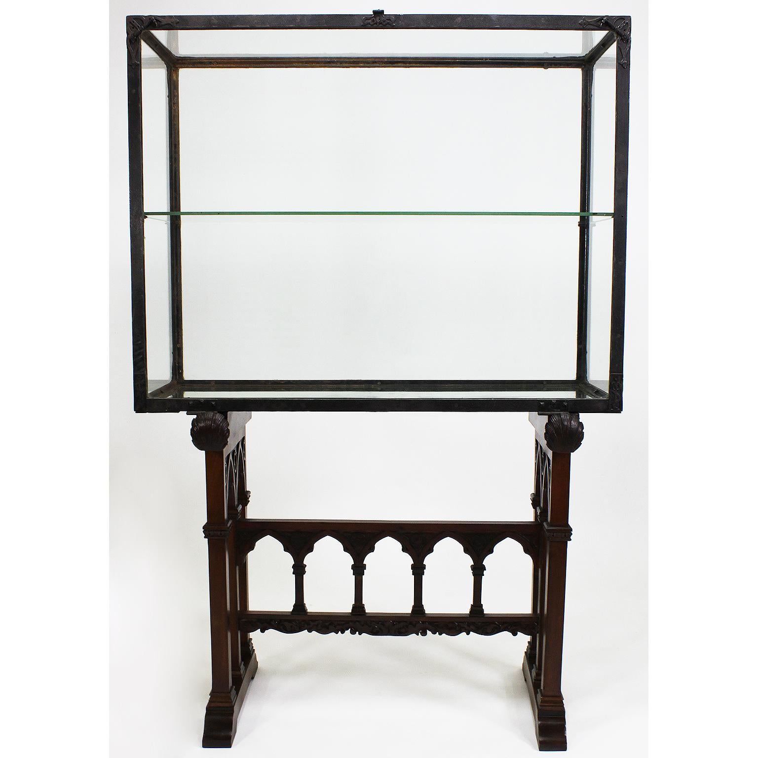 A Rare Spanish 19th-20th century Gothic Revival Baroque style carved mahogany and forged iron vitrine cabinet on stand. The rectangular hammered iron drop-front exhibition, display or jewelry cabinet with corner lock-hooks and a padlock-ready latch,
