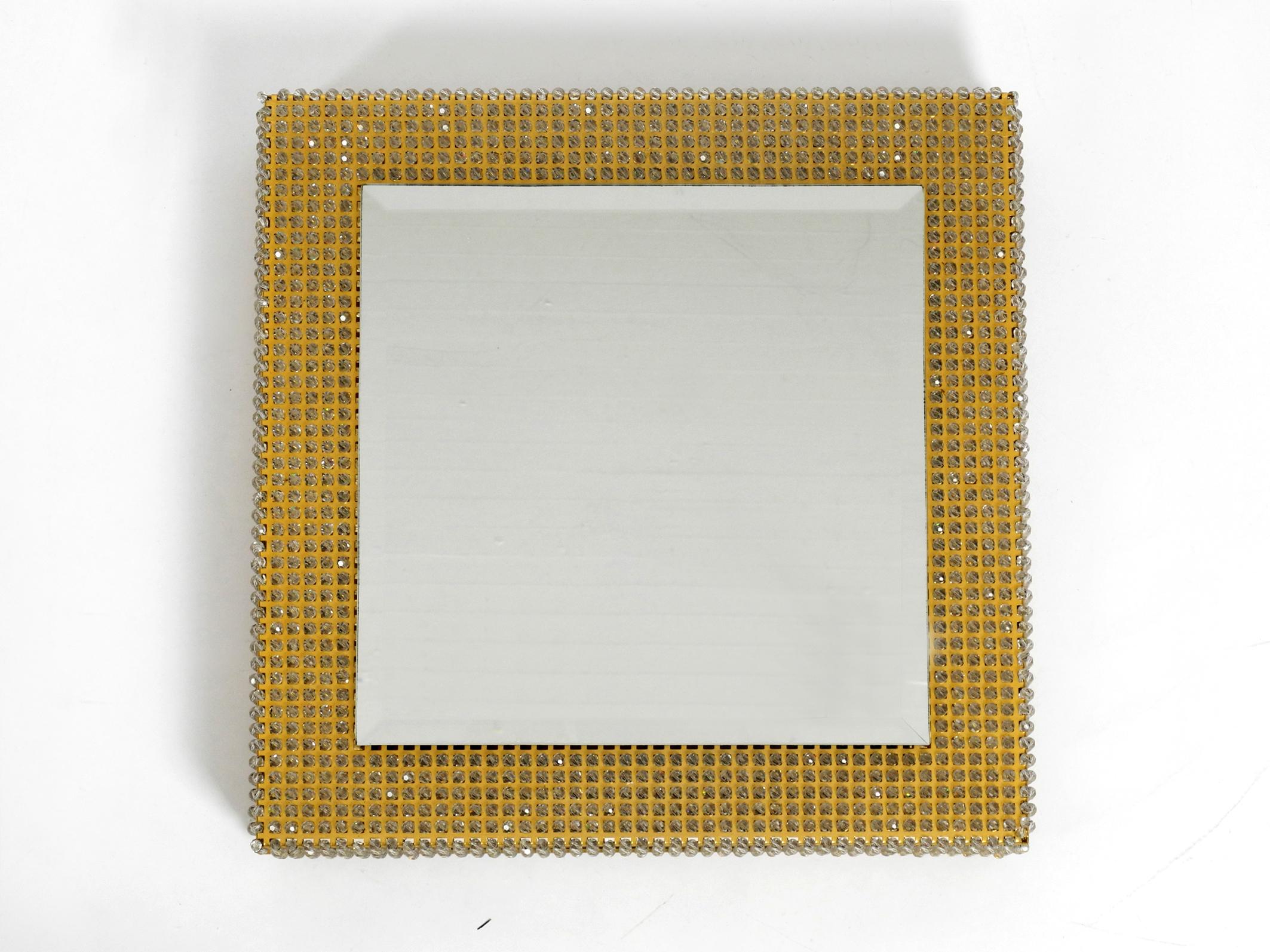 Beautiful background illuminated brass metal mirror from the early 1960s by Palwa.
Made in Germany. Very rare in this square design with a high frame full of crystal stones.
Great glare-free light. Very thick, massive cut mirror glass.
Mirror