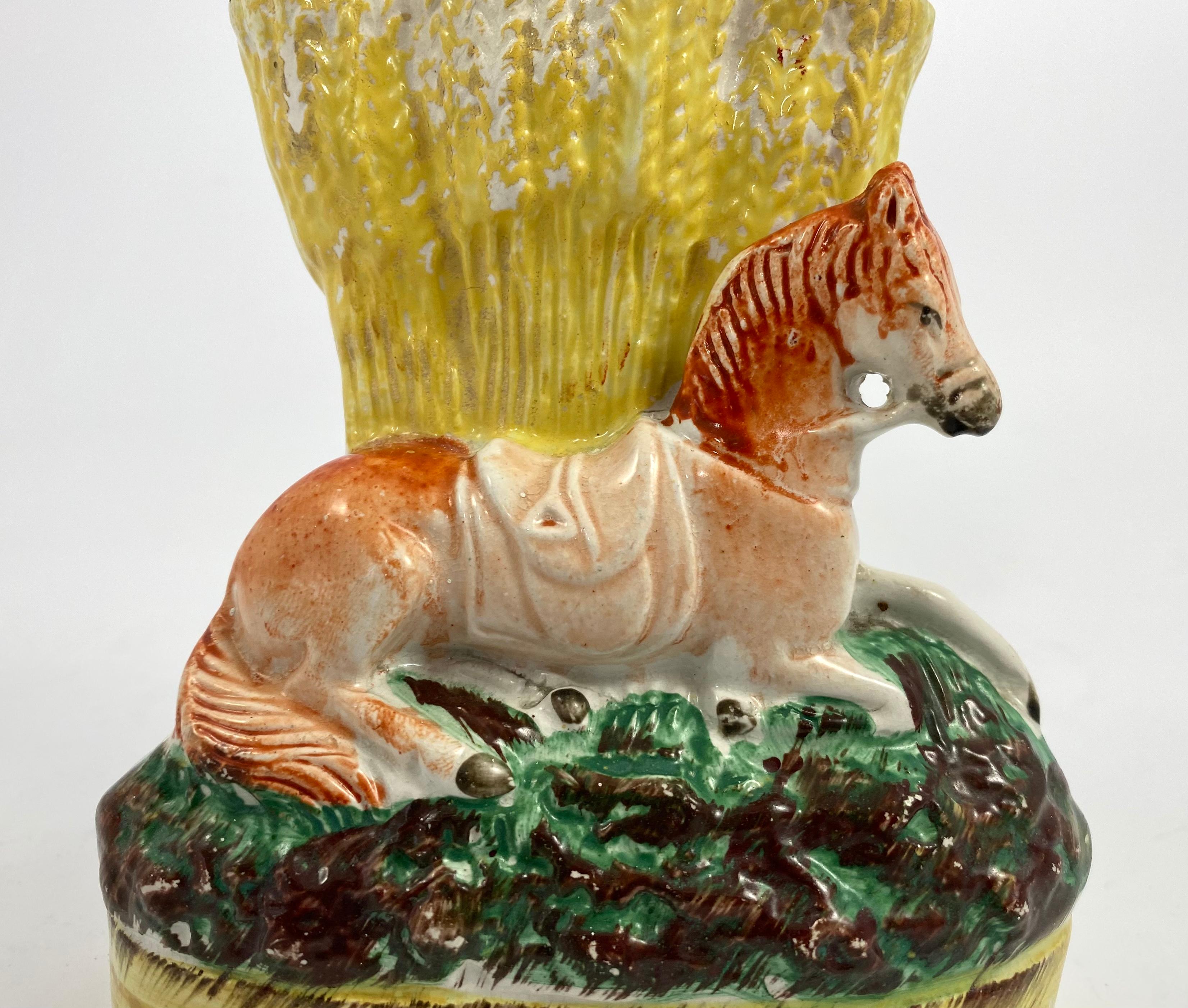 Rare Staffordshire pottery horse spill vase, c. 1860. Well modelled as a saddled horse, recumbent upon a grassy mound base, before a wheatsheaf spill vase. Painted in typical underglaze, and overglaze enamels.
Height: 14 cm, 5 1/2”.
Width: 11.5