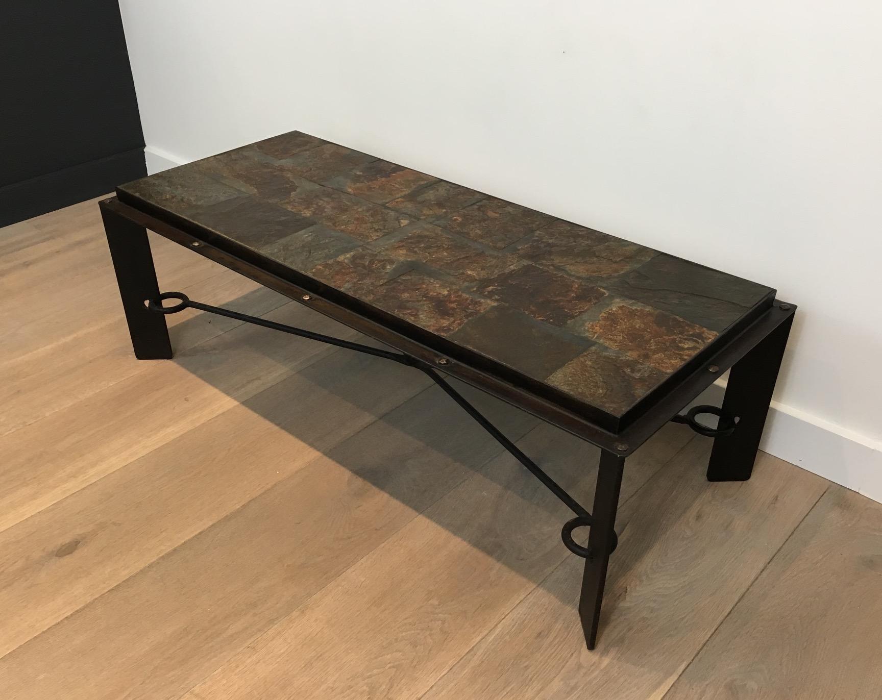 This unique and beautiful coffee table is made of steel and iron with a lava stone top. This is a very interesting design with forged iron and large rivets all around the top frame. The top is made of beautiful patchwork lava stone tiles. This is a