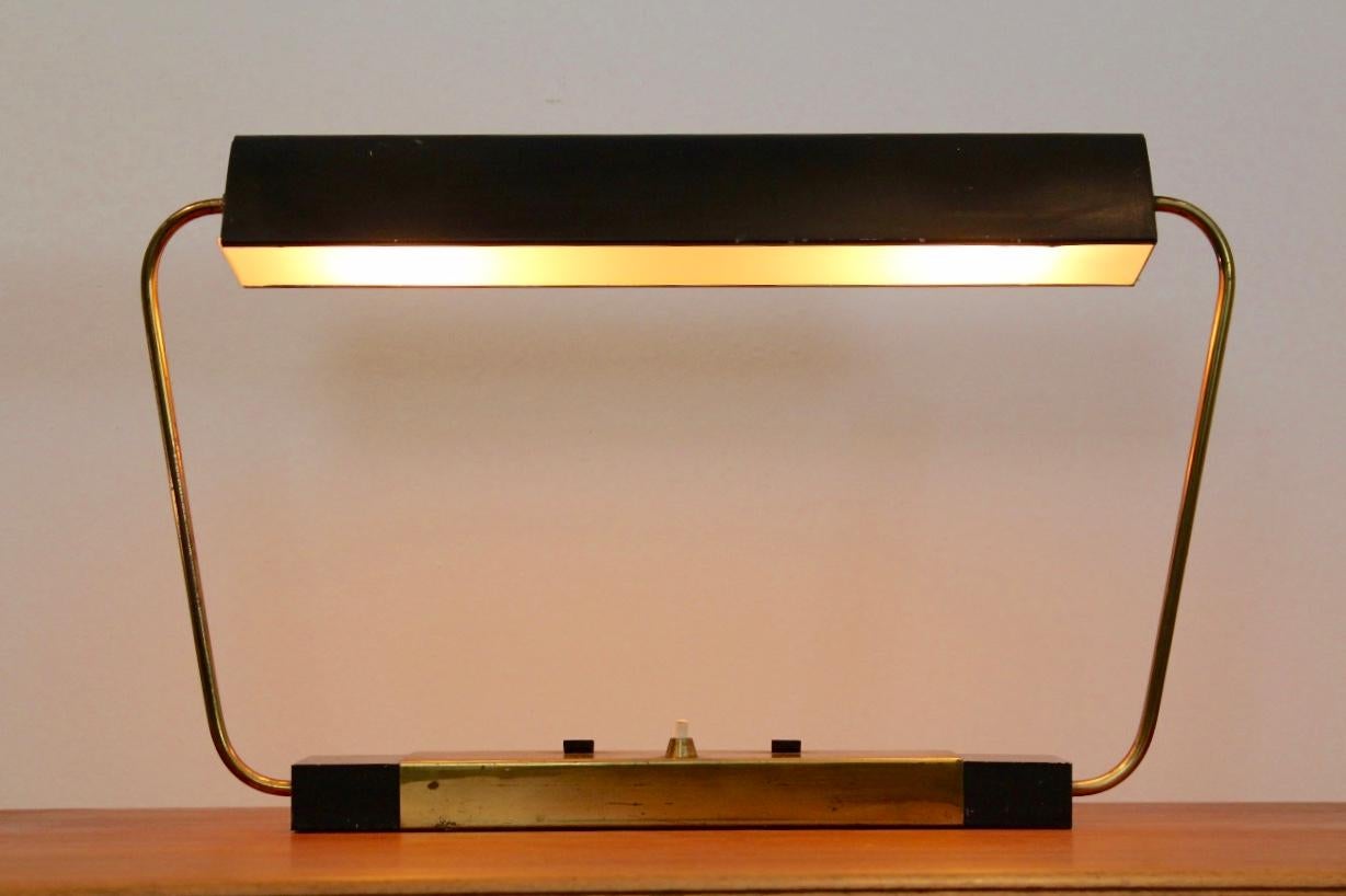 Highly rare and beautiful Stilnovo table lamp in perfect condition. Produced during the 1960s and in perfect original condition. Brass arms holding an adjustable black metal lampshade which can rotate back and forth. Black metal base, brass-plated