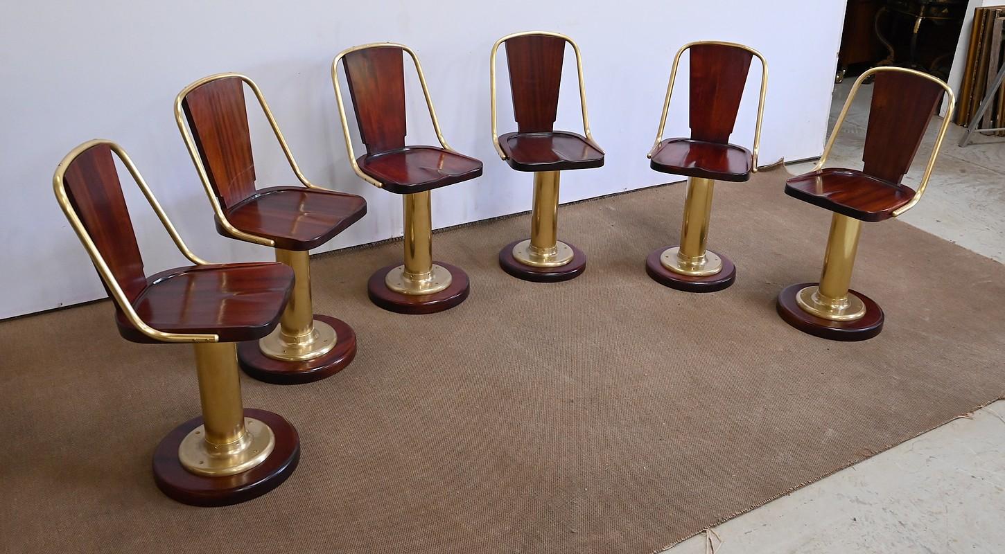 Superb English-made nautical furniture dating from the early 20th century.
Each of these six swivel seats is made of mahogany and brass. A mahogany seat base rotates, its slightly rounded edge resting on a brass element secured by four screws. The