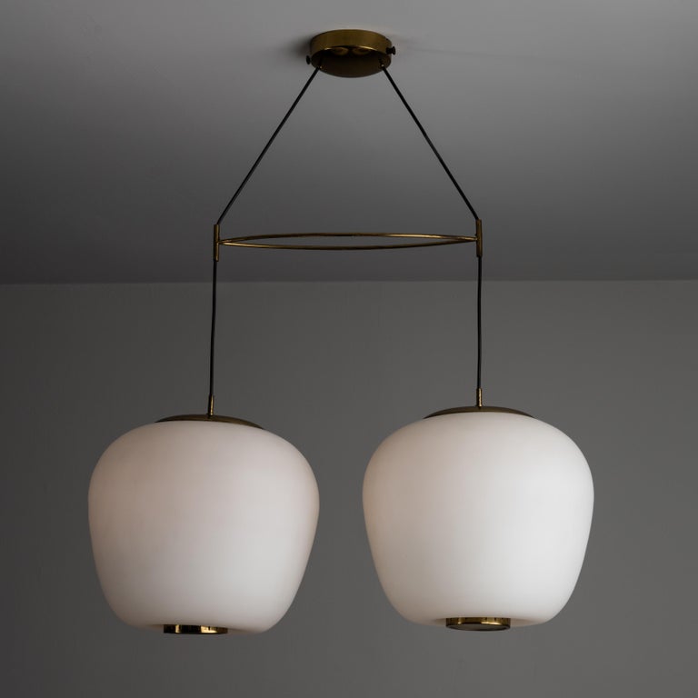 Rare double-shade suspension light by Stilnovo. Designed and manufactured in Italy, circa 1950s. Sleek double shade suspension light featuring soft opaline glass shades with polished brass finials and framework. Minimal oval pointed center spacer