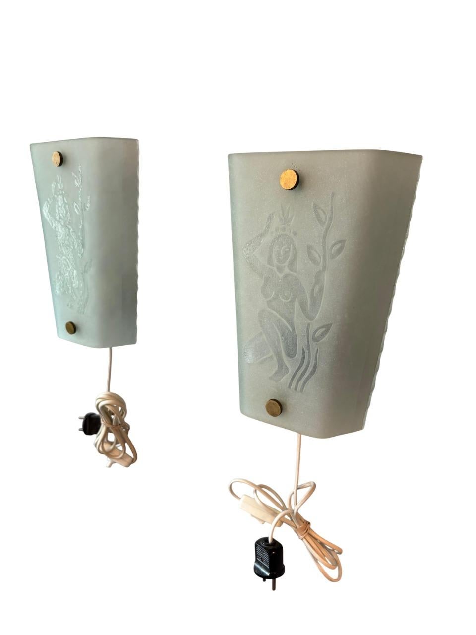 Una rara coppia di lampade da parete attribuite al designer svedese Glössner, risalenti agli anni '30-'40. Ogni paralume in vetro smerigliato è inciso con una figura femminile stilizzata circondata da motivi naturali, che riflette la miscela di