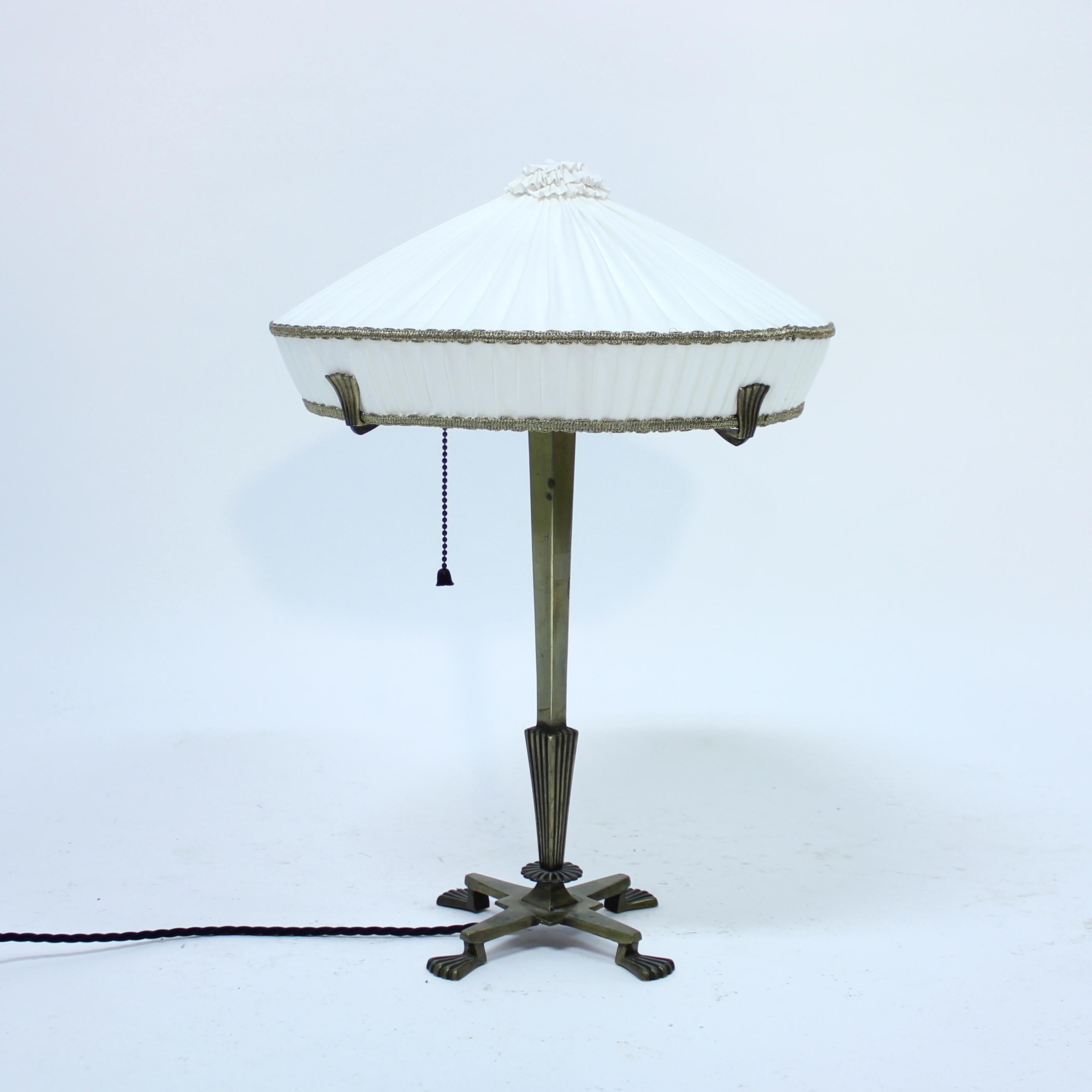 Lámpara de sobremesa Art Déco de latón del fabricante CG Hallberg de los años 20 y atribuida a la diseñadora Elis Bergh. Un bonito y limpio diseño Art Déco típico con forma de globo en la parte inferior del tallo, justo encima de la base redonda.