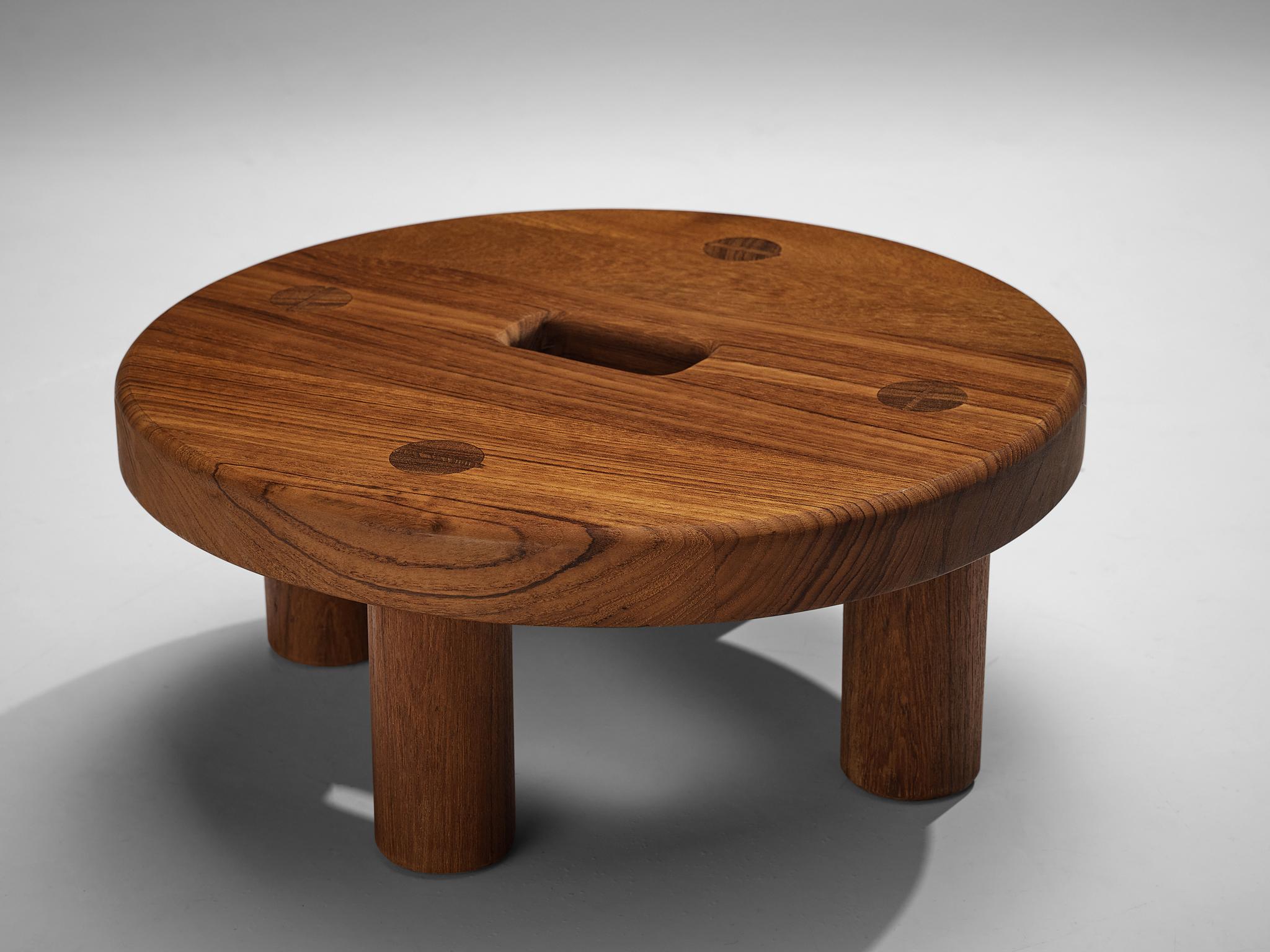 Swedish round stool, teak, Sweden, 1950s.

A heavy and thick stool has a round top with rectangular gap in the middle. The top also features the dynamic grain of the wood and the connective joints of the four circular legs. The teak wood has a