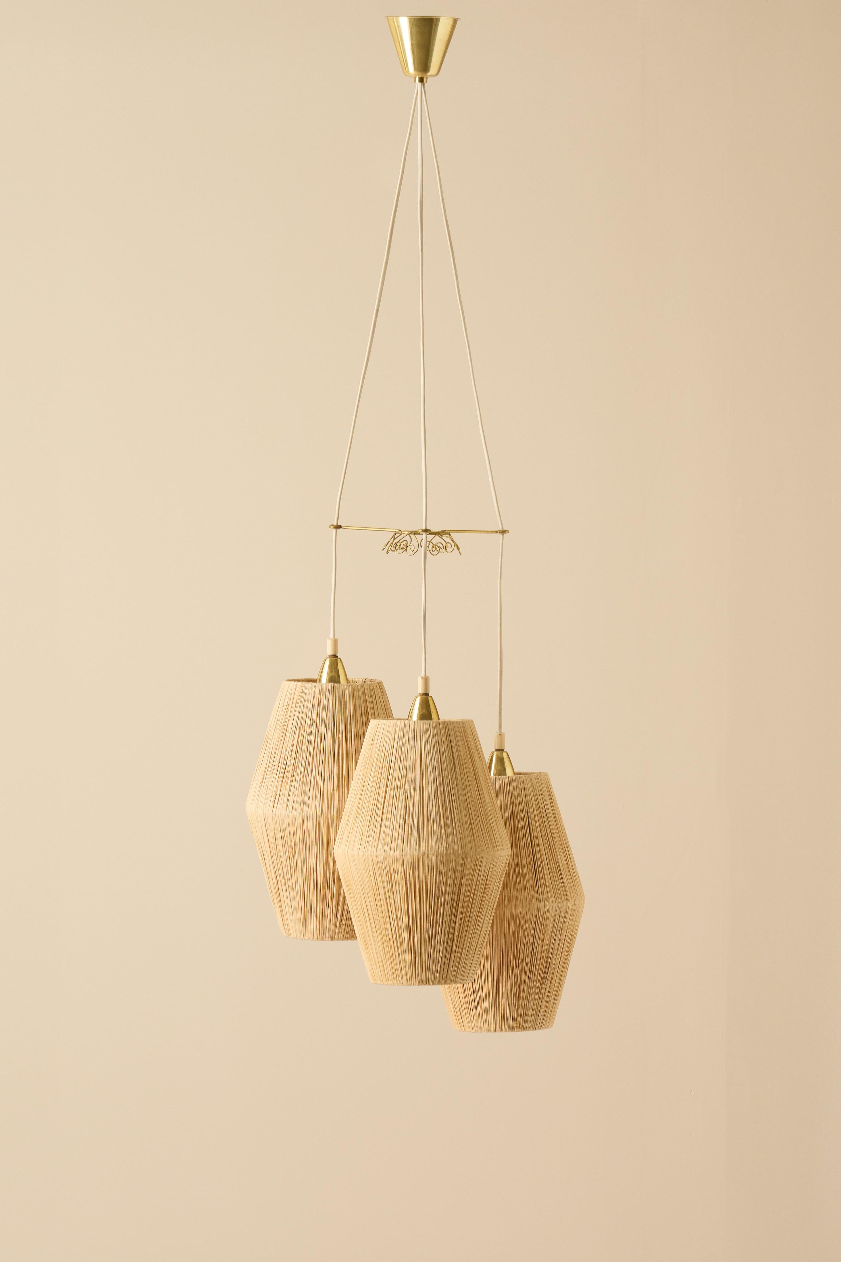 Plafonnier moderne suédois de taille généreuse, fabriqué en Suède vers les années 1940 par un fabricant non identifié.
Cet élégant luminaire minimaliste comprend trois pendentifs avec un répartiteur de cordon décoratif en laiton et des supports de