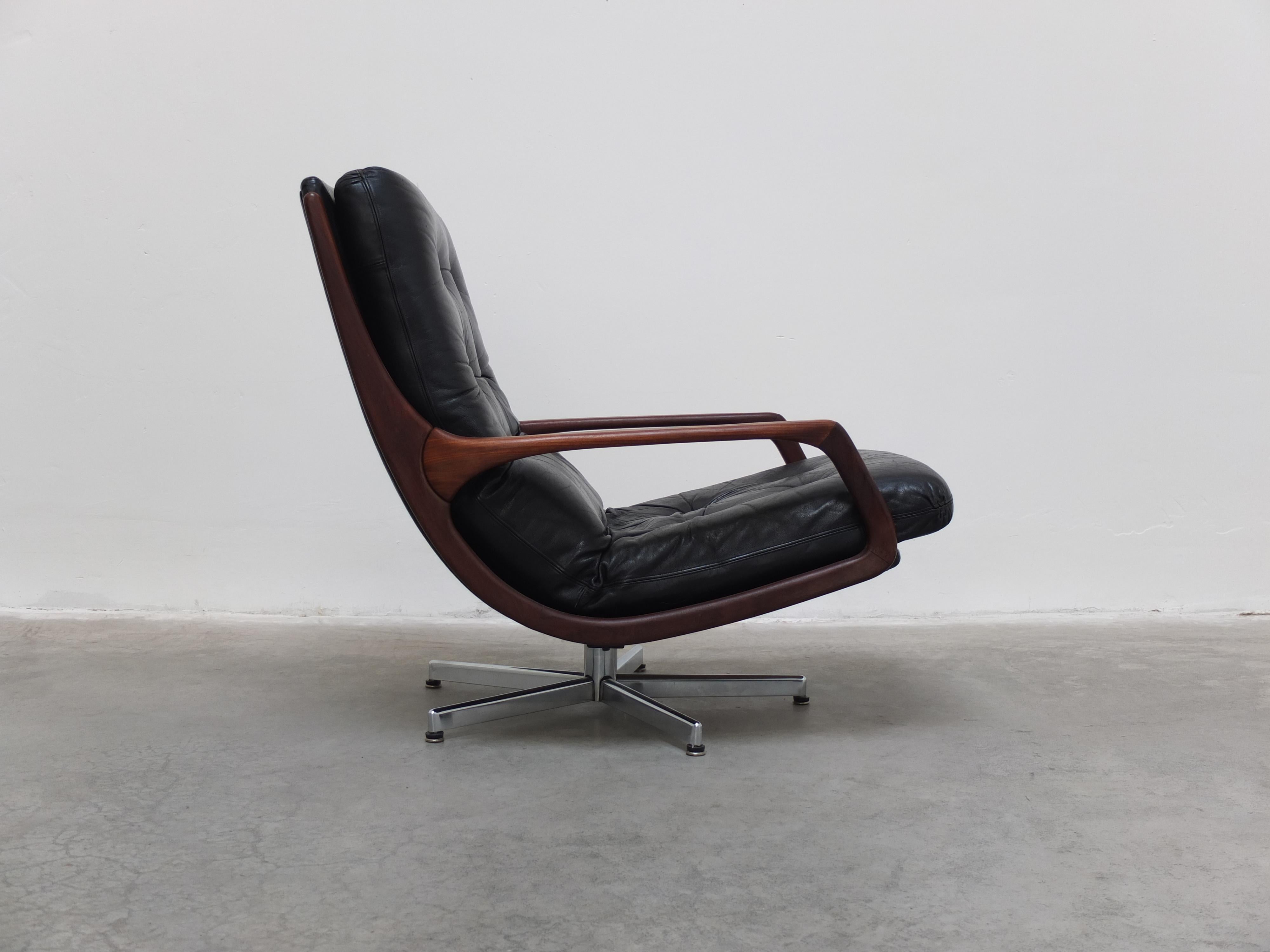 Chaise de salon moderniste très cool conçue par Eugen Schmidt pour Soloform vers 1960. Cuir noir original et accoudoirs en noyer combinés à un élégant piétement métallique pivotant. La combinaison des matériaux et la forme unique font que cette
