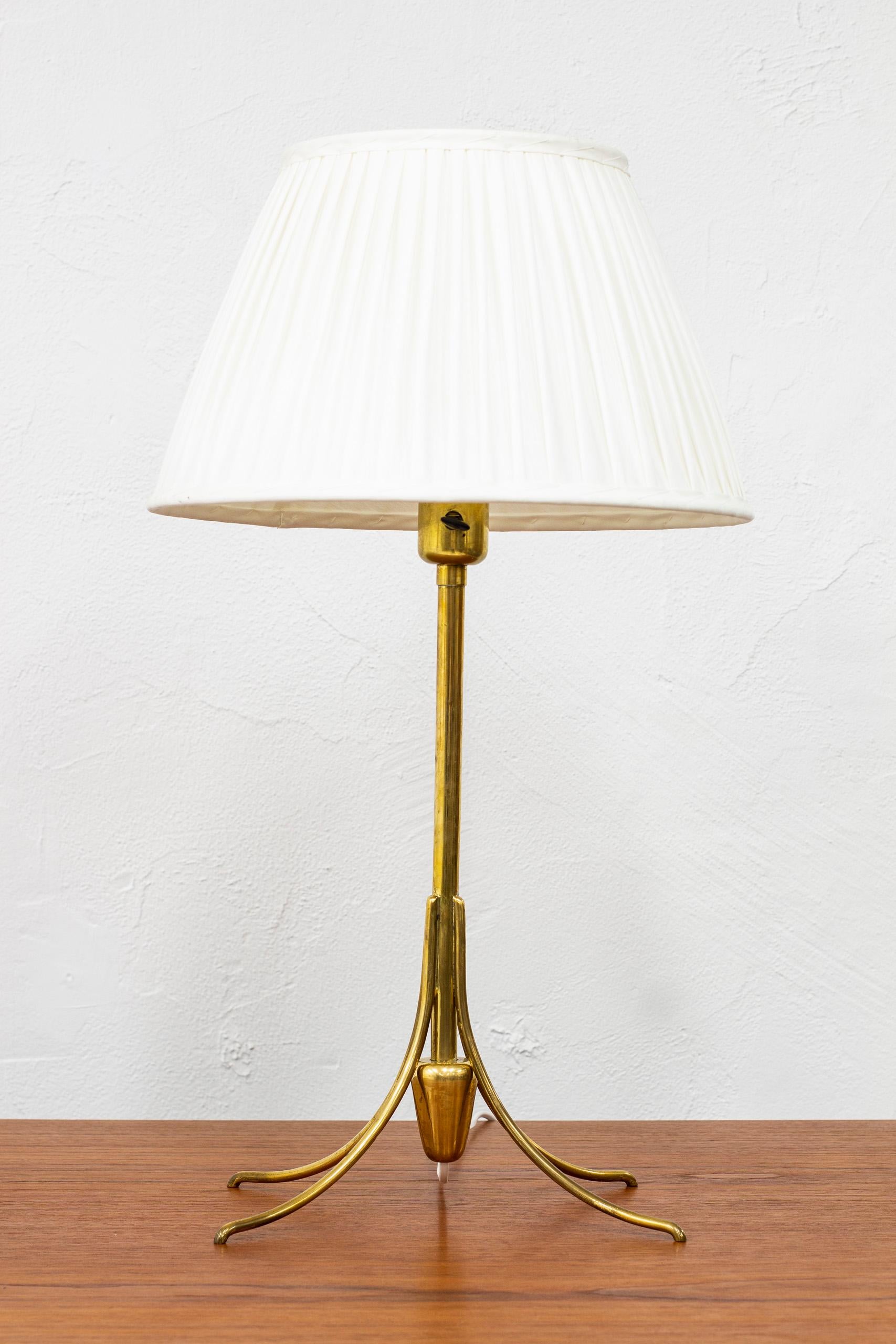 Rare table lamp designed by Bertil Brisborg. Produced by Nordiska Kompaniet during the 1940s. Made from solid polished brass. With new lamp shade upholstered with cream colored chintz fabric. Turning light switch on the lamp in working order. Very