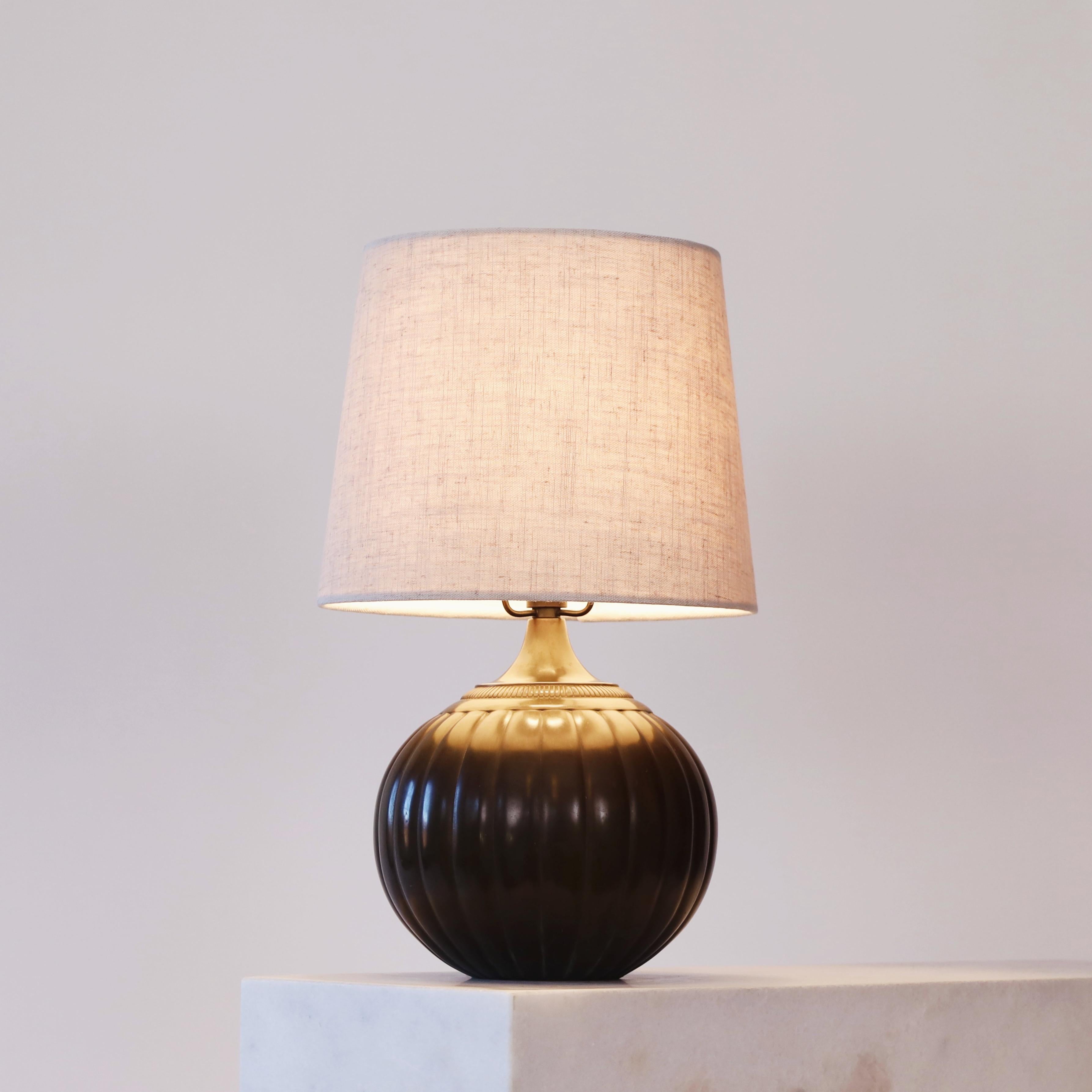 A rare table lamp designed by Just Andersen in 1934. A classic piece of Danish design history for a beautiful home.  

* A round metal lamp with vertical lines and a beige fabric shade
* Designer: Just Andersen
* Model: 1632 (stamped ‘Just 1632’)
*