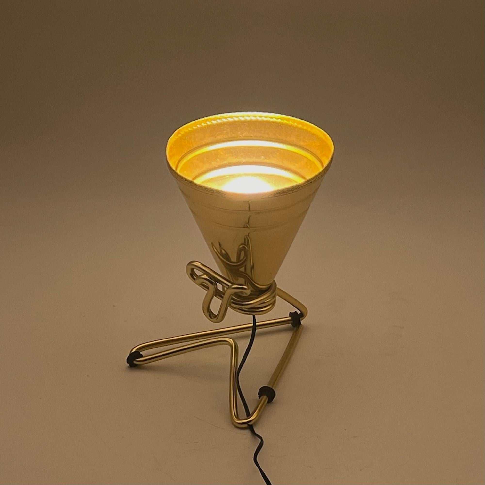 Rare and iconic lamp conceived by the creative genius of Ettore Sottsass and produced by Rinnovel in the 1950s.

This artisanal lamp features a distinctive aluminium cone lampshade with a shining golden hue, supported by a metal frame representing a