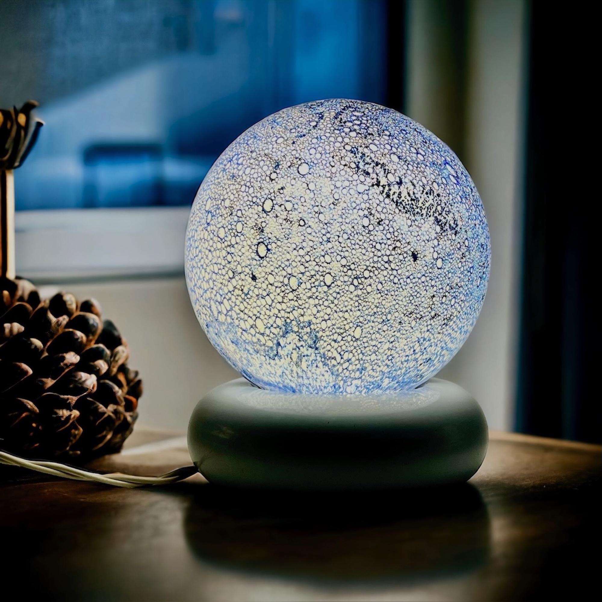 Magnifique lampe de table 'Lume Temptation' par Targetti Sankey, un exemple frappant du design italien des années 70, avec un globe en verre bleu moucheté sur une base en métal blanc. Une lampe au design intemporel qui offre un éclairage envoûtant