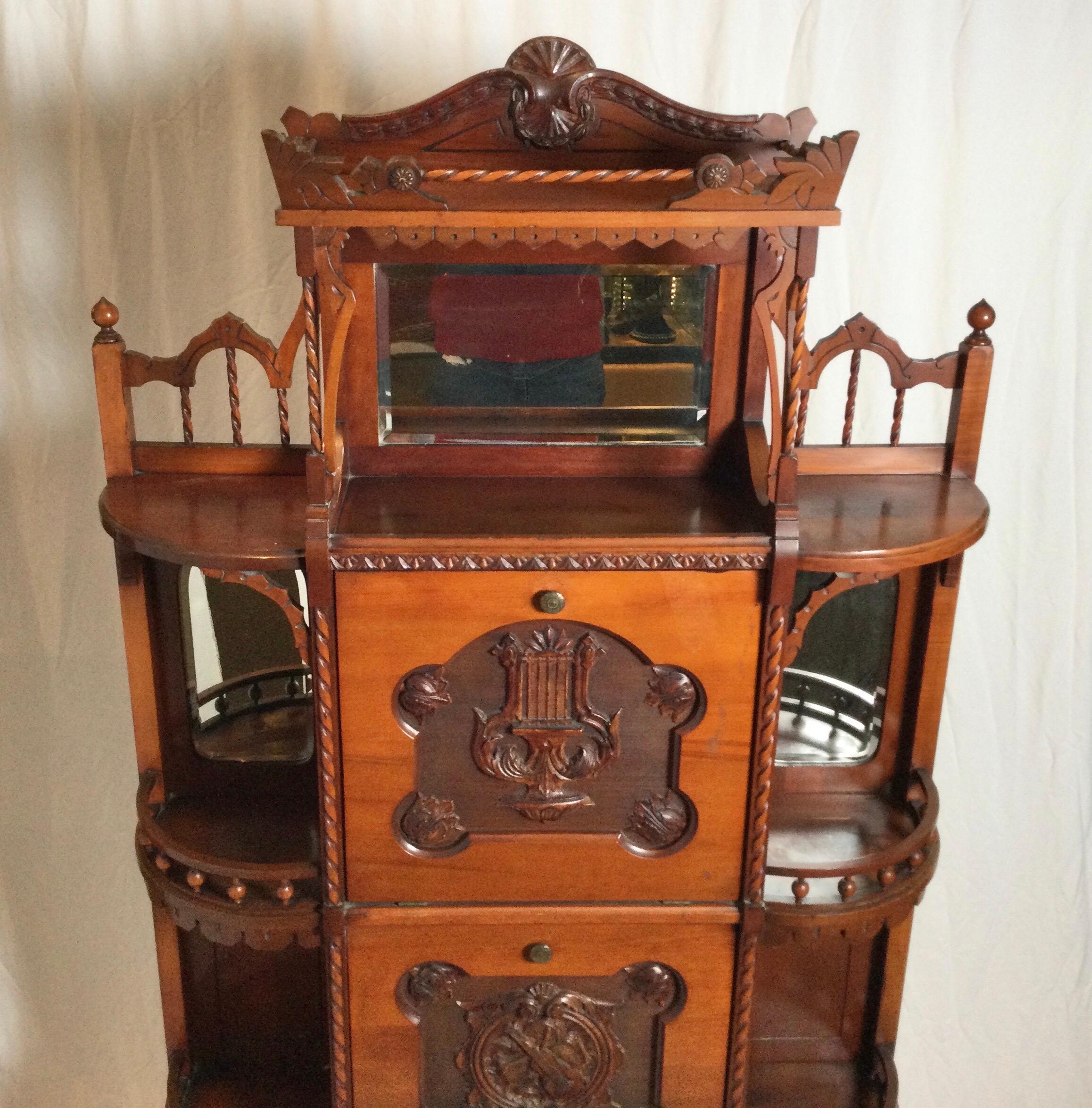 Elaborate design Antique music cabinet with two pull drawers that hold sheet music. The fronts with hand carved violin and lyre design. The open etagere sides with mirrored panels.