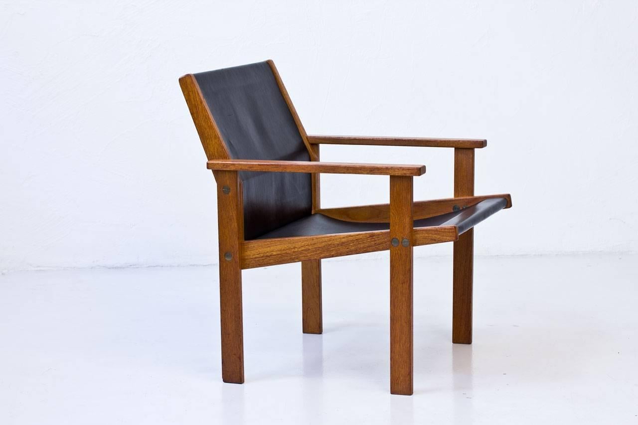 Rare easy chair designed by Hans-Agne Jakobsson. Made by cabinetmaker Bertil Johansson at Markaryd in Sweden in 1976. Solid teak frame with thick black leather seat and backrest. Brass hardware.