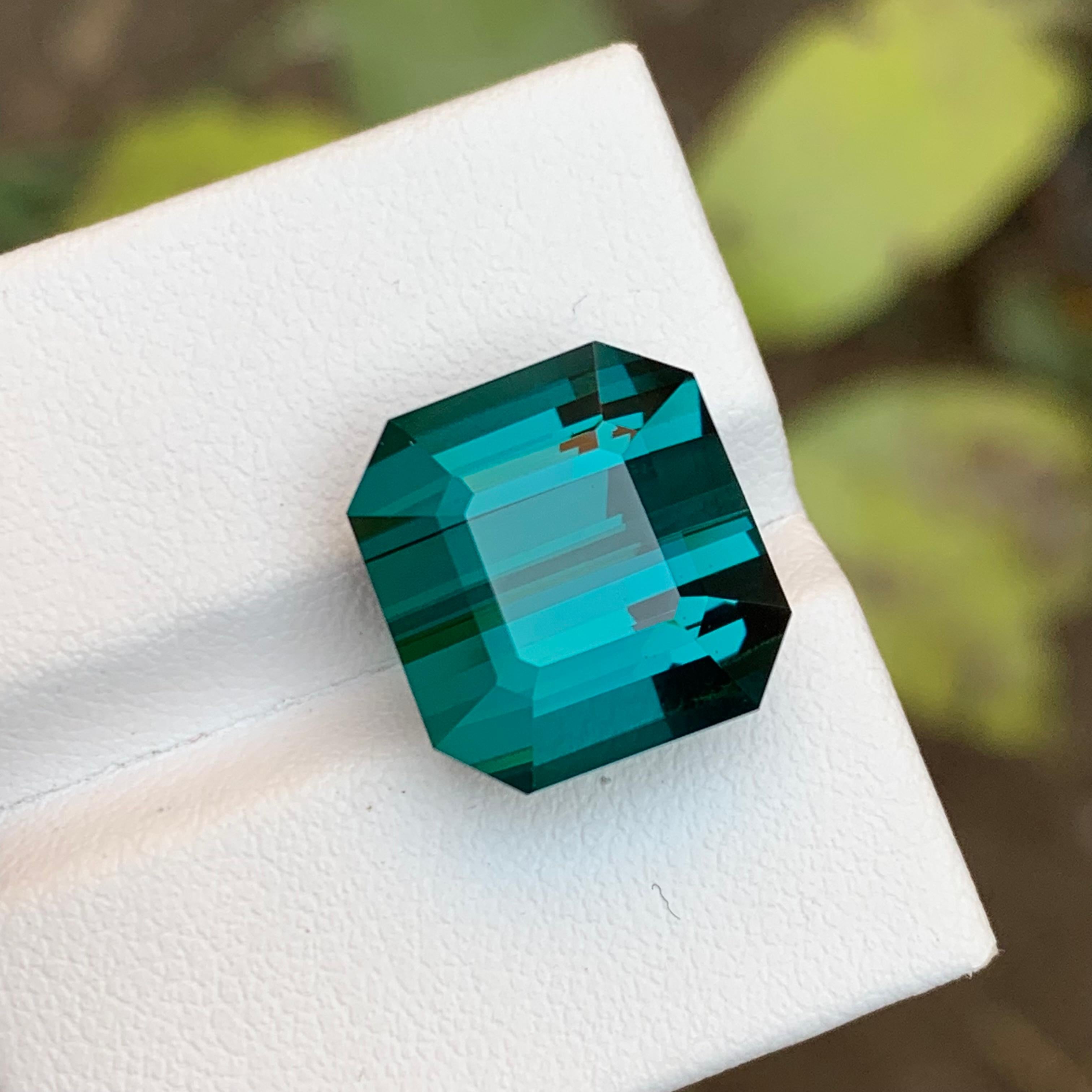 GEMSTONE TYPE: Tourmaline
PIECE(S): 1
WEIGHT: 15.30 Carats
SHAPE: Emerald
SIZE (MM):  13.02 x 13.83 x 10.03
COLOR: Teal Blue
CLARITY: Loupe Clean
TREATMENT: Not treated
ORIGIN: Afghanistan
CERTIFICATE: On demand

Behold, a treasure nestled amidst
