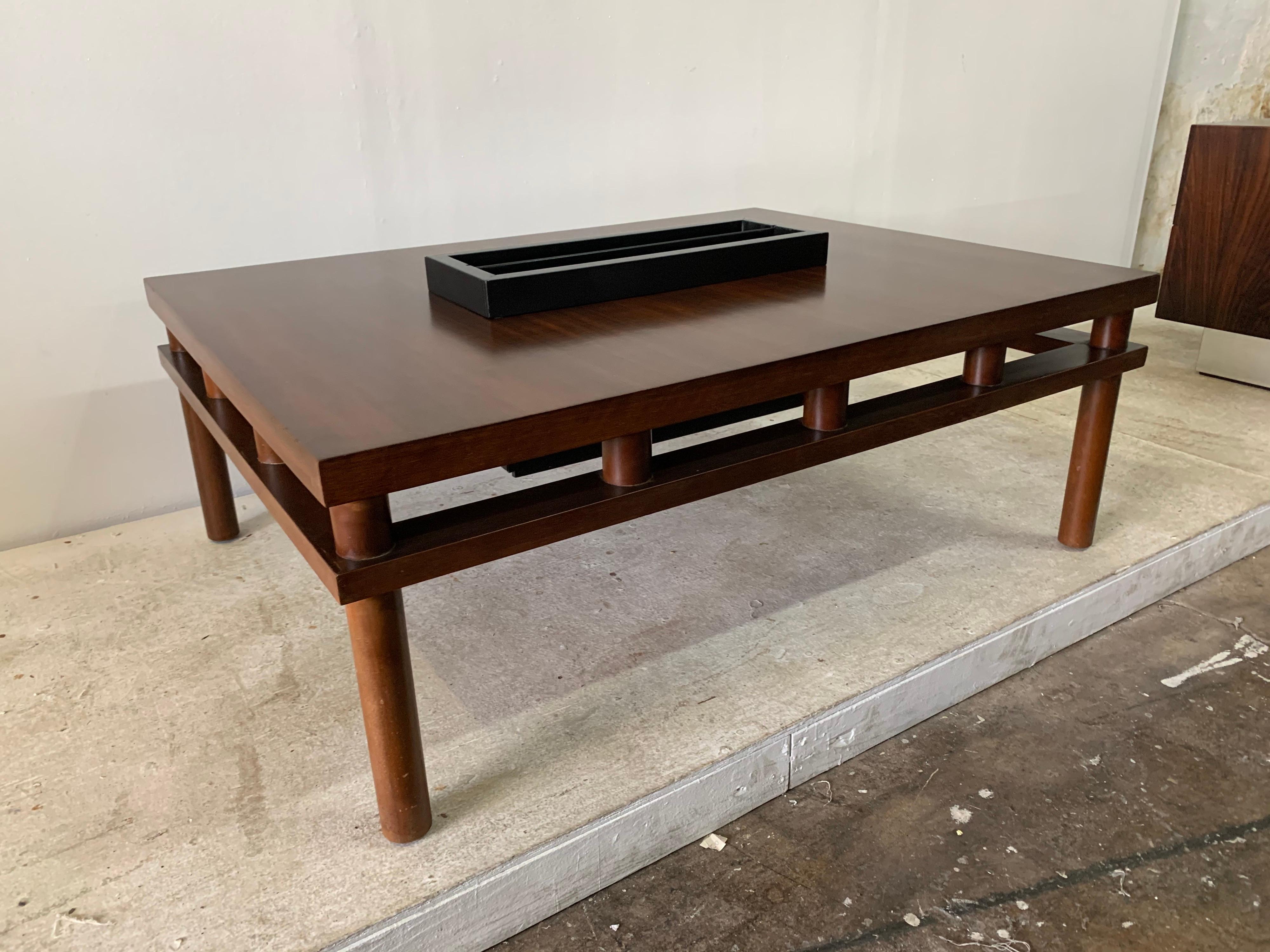 A rare midcentury design by T. H. Robsjohn-Gibbings coffee table with center magazine holder box which is removable. A rich dark finish and black matte magazine box. Original label to underside dated 1952.