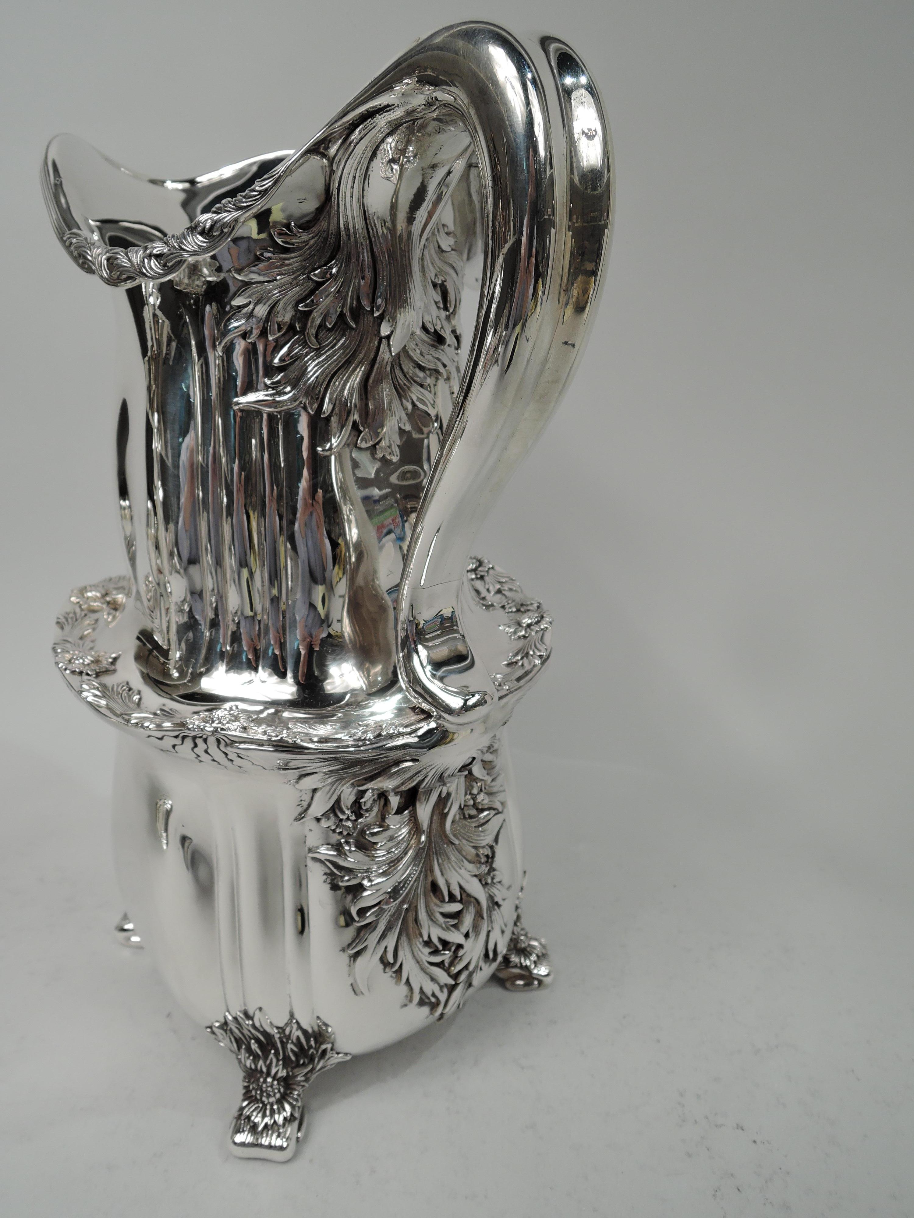 Rare Chrysanthemum sterling silver water pitcher. Made by Tiffany & Co. in New York. Double-gourd with irregular fluting; helmet mouth with leaves wrapped around reeded rim. Shoulder has applied leaf and flowerhead border with radiating squiggles