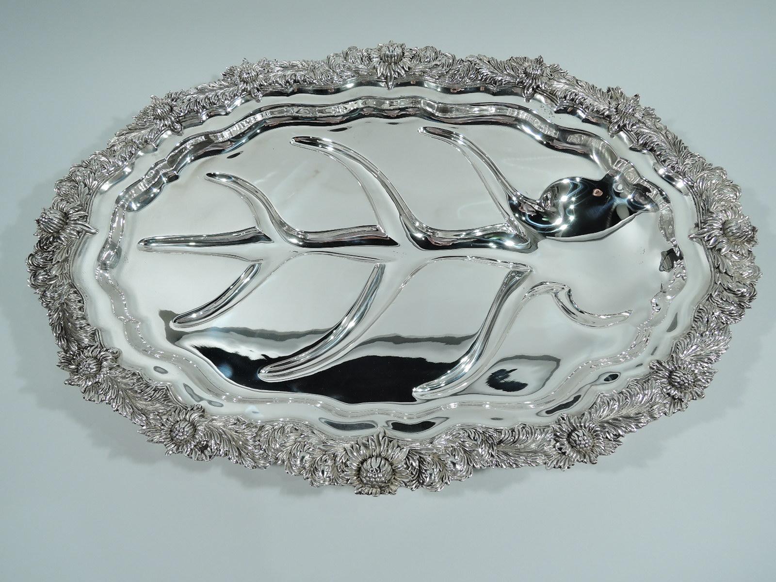 Chrysanthemum sterling silver meat platter. Made by Tiffany & Co. in New York. Shaped oval well with tree of life to collect the rivulets of precious pan juices. Irregular rim with the famous chrysanthemum flower heads alternating with leaves in