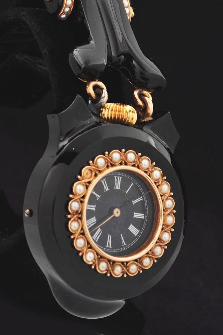 Extremely rare Tiffany & Co. black onyx and pearl lapel watch with 18-karat yellow gold bezels, links, hinge and pin with original Tiffany & Co. fitted box, circa 1878. Outer gold bezel is set with seed pearls. Case measures 37mm across, and is