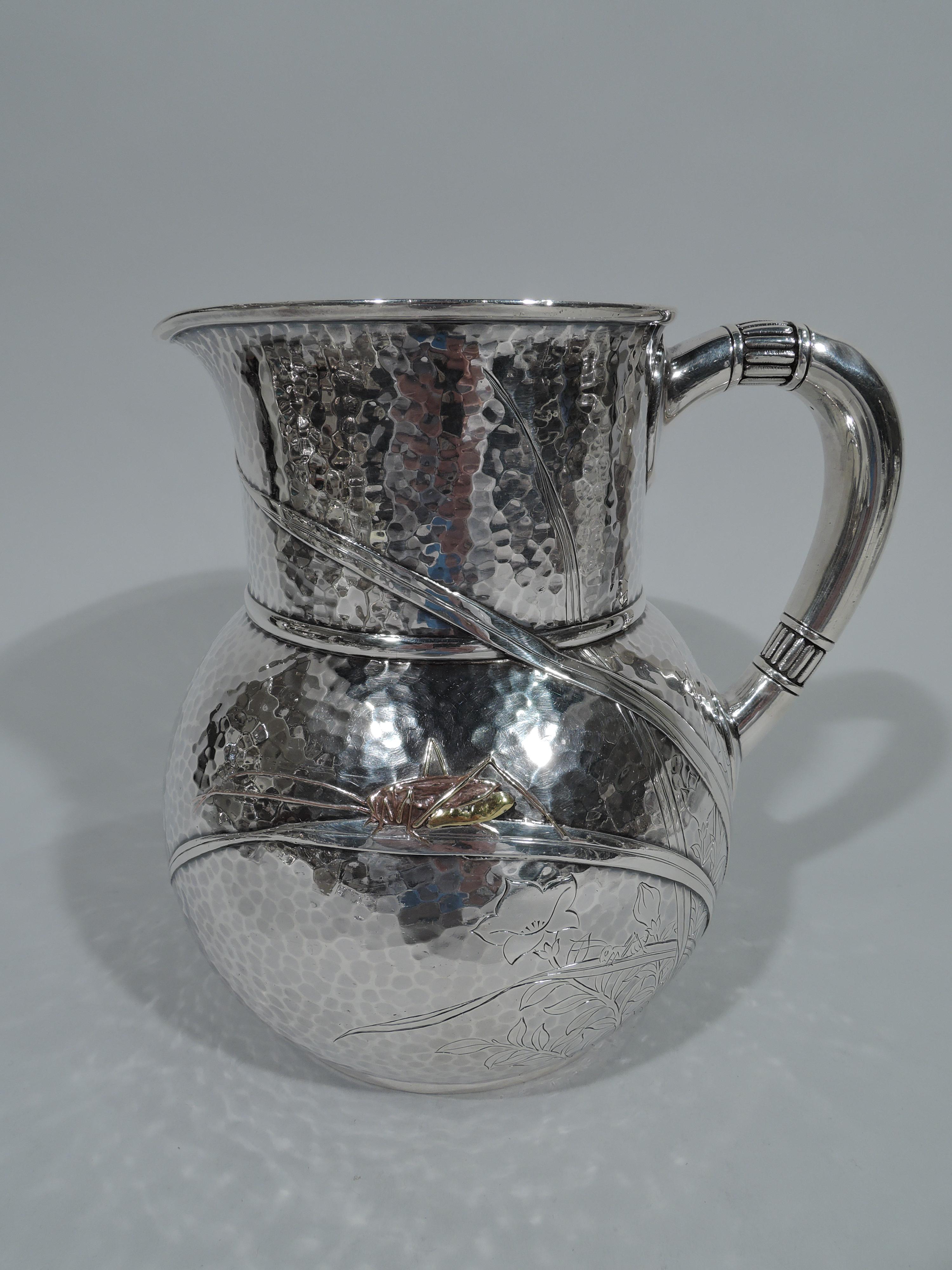 Rare mixed metal pitcher with lots of bugs. Made by Tiffany & Co. in New York. Globular with drum-form neck, small lip spout, and c-scroll handle. Modish insects—dragon fly, grasshopper, and butterfly—creep and dart among fluid and interlaced grass