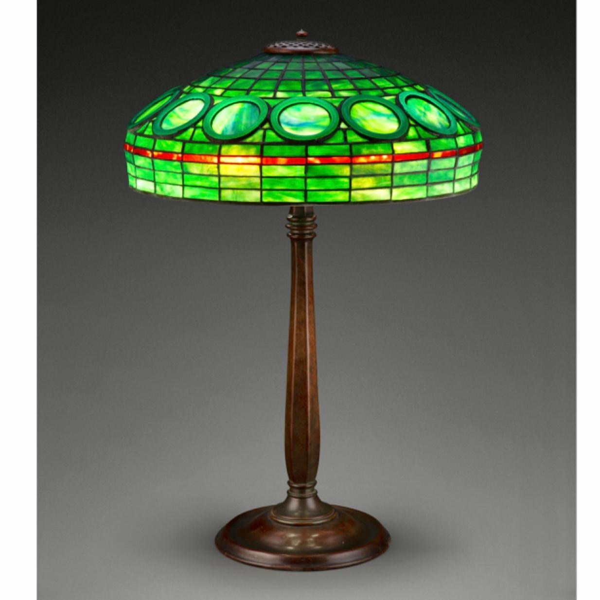 Rare lampe de table géométrique en verre au plomb et bronze patiné des studios Tiffany, vers 1910.
Il s'agit d'une rare lampe de table de grande taille, unique en son genre, des premiers studios Tiffany, illustrée dans le catalogue Raisonne