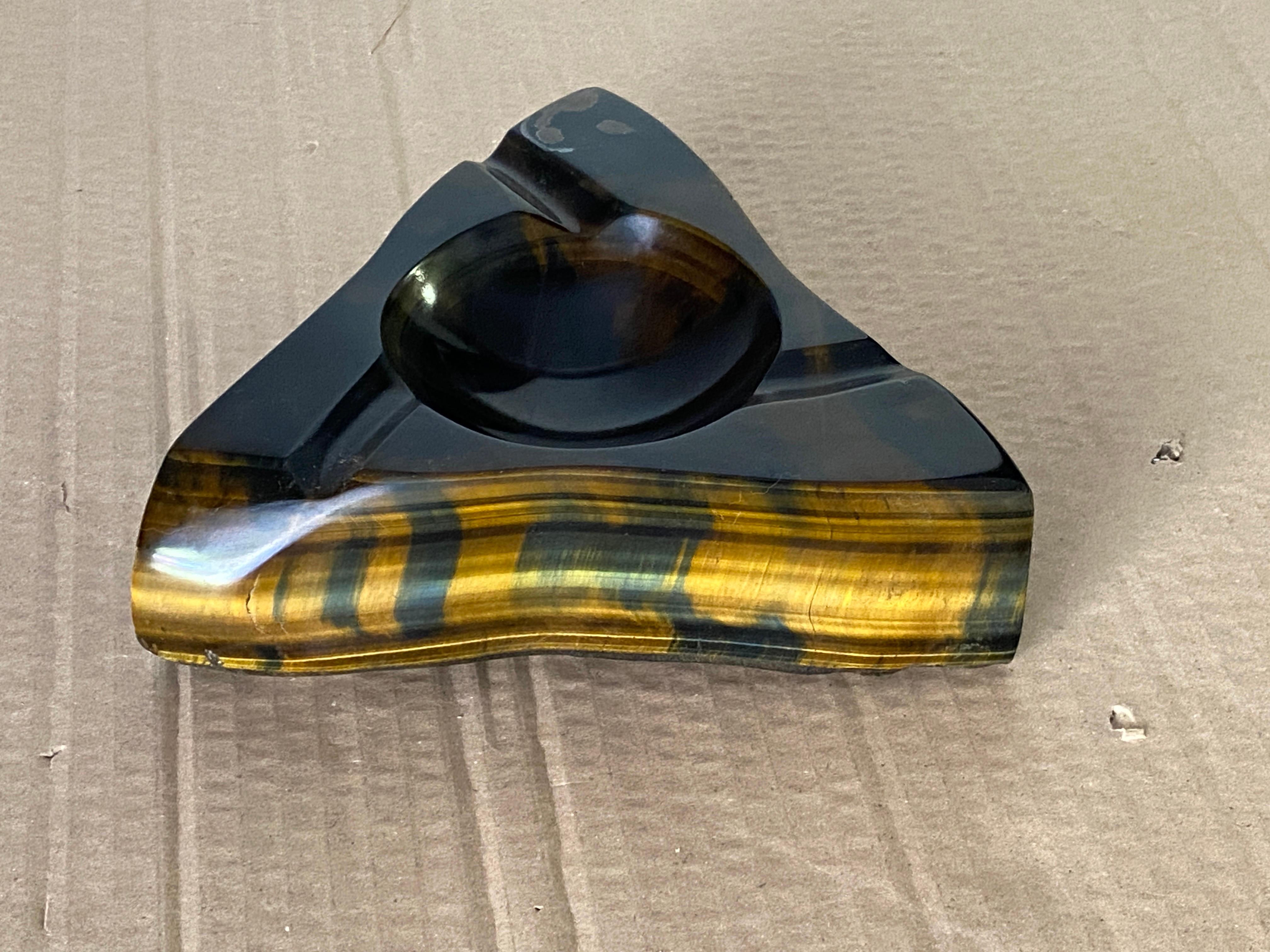 Solid tiger eye stone ashtray, polished, from South Africa. 
Tiger's eye is a mineral with a silky lustre and distinctive red-brown golden coloring. In the 16th century it was more precious than gold, often used as eyes in deity statues, also worn