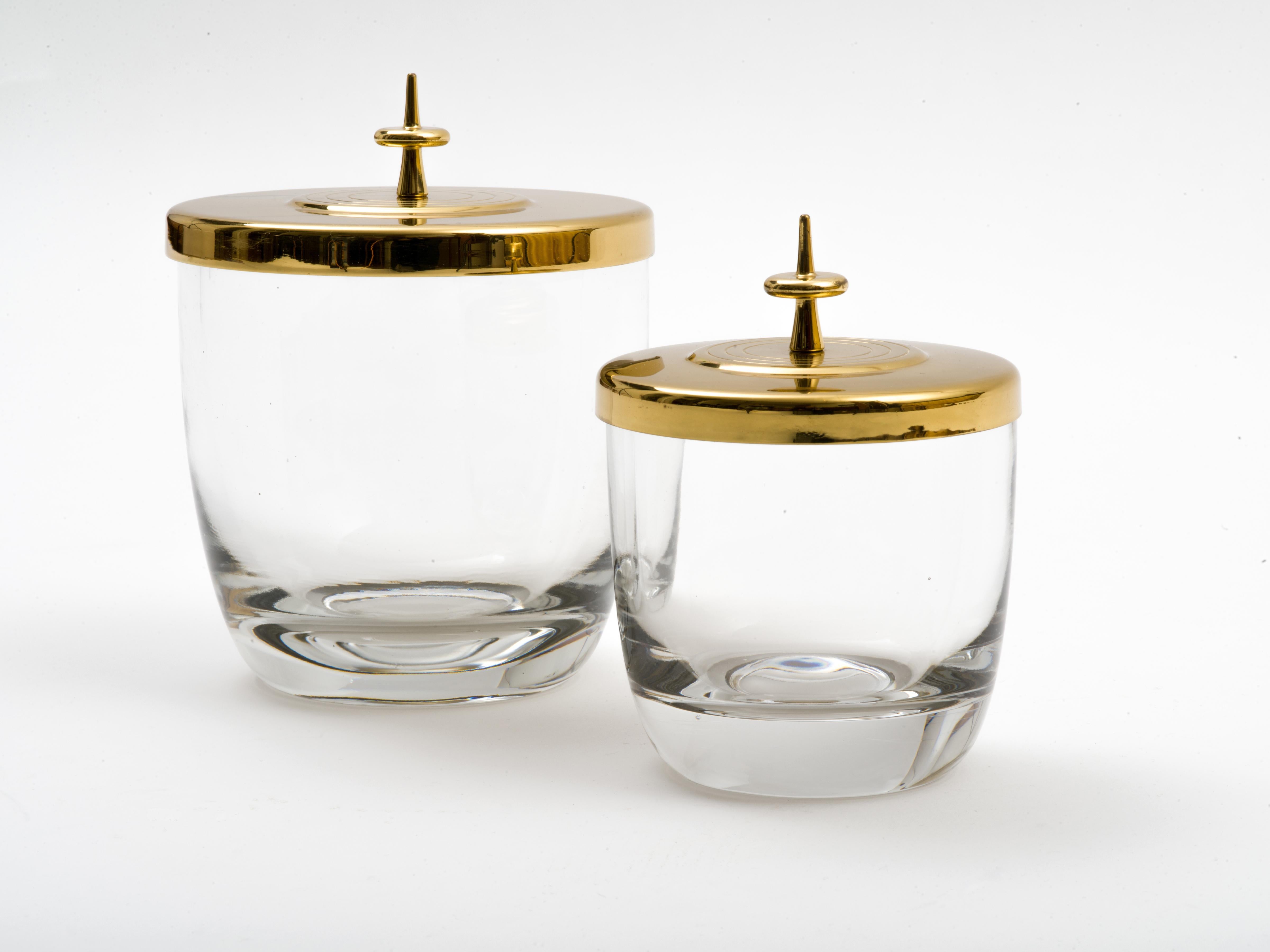 An exceptional and rare Tommi Parzinger design for Dorlyn Silversmiths. A pair of thick, mold-blown glass bowls or jars with lacquered brass lids executed in Parzinger's signature modernist style. These have substantial weight and presence and lend