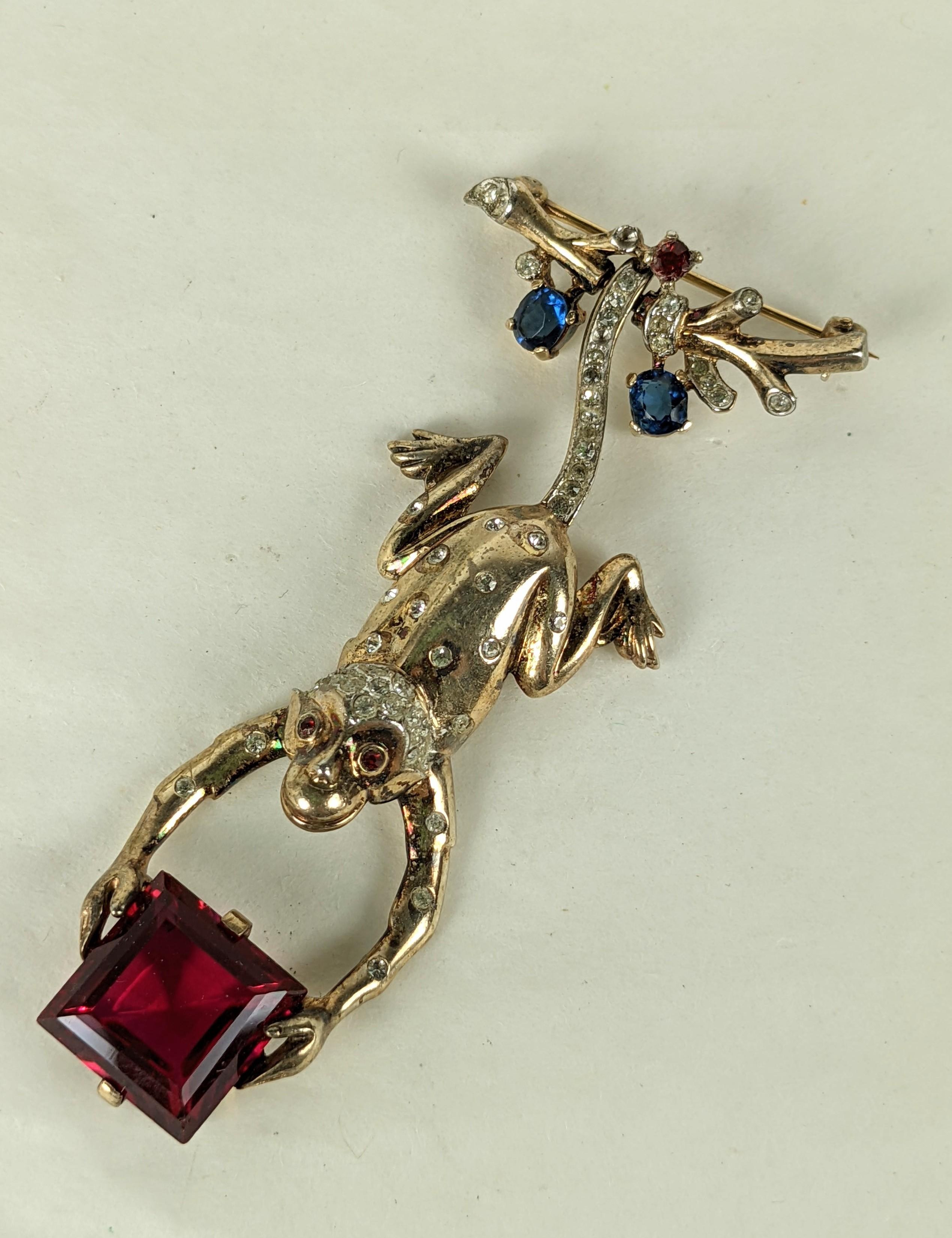 Rare, Collector quality Trifari Hanging Monkey Brooch, by Alfred Phillipe in sterling vermeil with pastes. Charming articulated design which allows monkey to hang from a branch clutching a square cut ruby. 1940's USA. 2.75