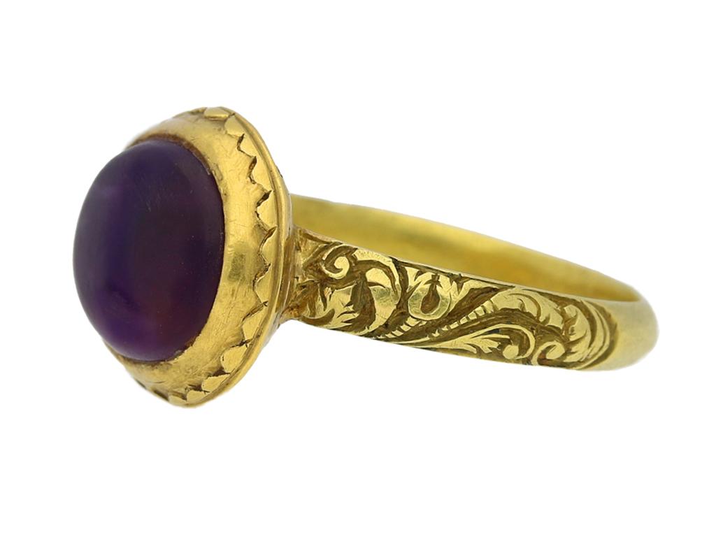 Rare Tudor amethyst ring. Set with an oval cabochon amethyst in a closed back rubover collet setting, encircled by a delicate scalloped gold frame, and with finely pierced vertical openwork detail to the gallery, flanked by intricately carved