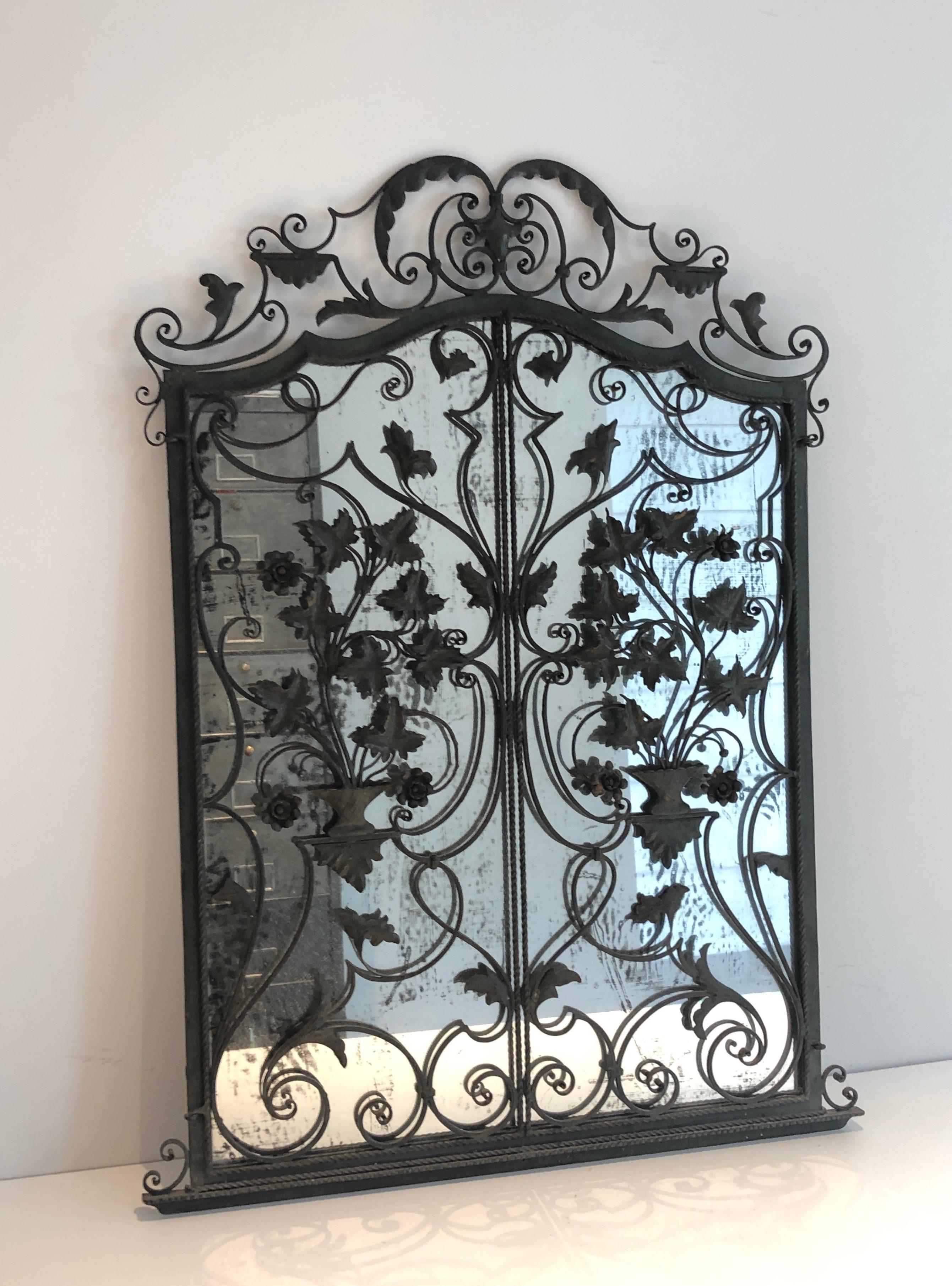 This rare two opening panels mirror is made of a delicate wrought iron work with leaves and scrolls and a nice faux-antiques eglomized mirror. This is a French work, circa 1940.