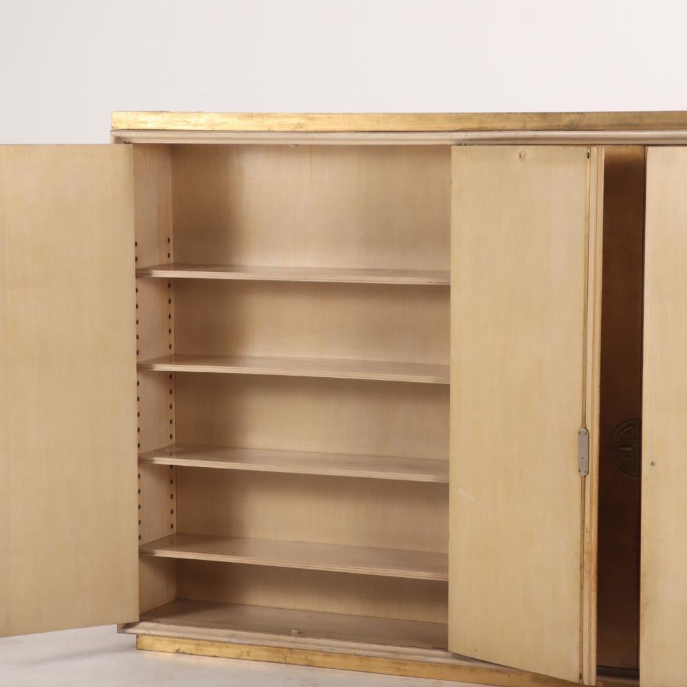 Grande e raro armadio a due pezzi in legno e pergamena C 1950, alla maniera di James Mont. Il pezzo superiore è un armadio a muro sospeso con un'area espositiva centrale a specchio dietro due ante, affiancata da altre 4 ante. La sezione inferiore