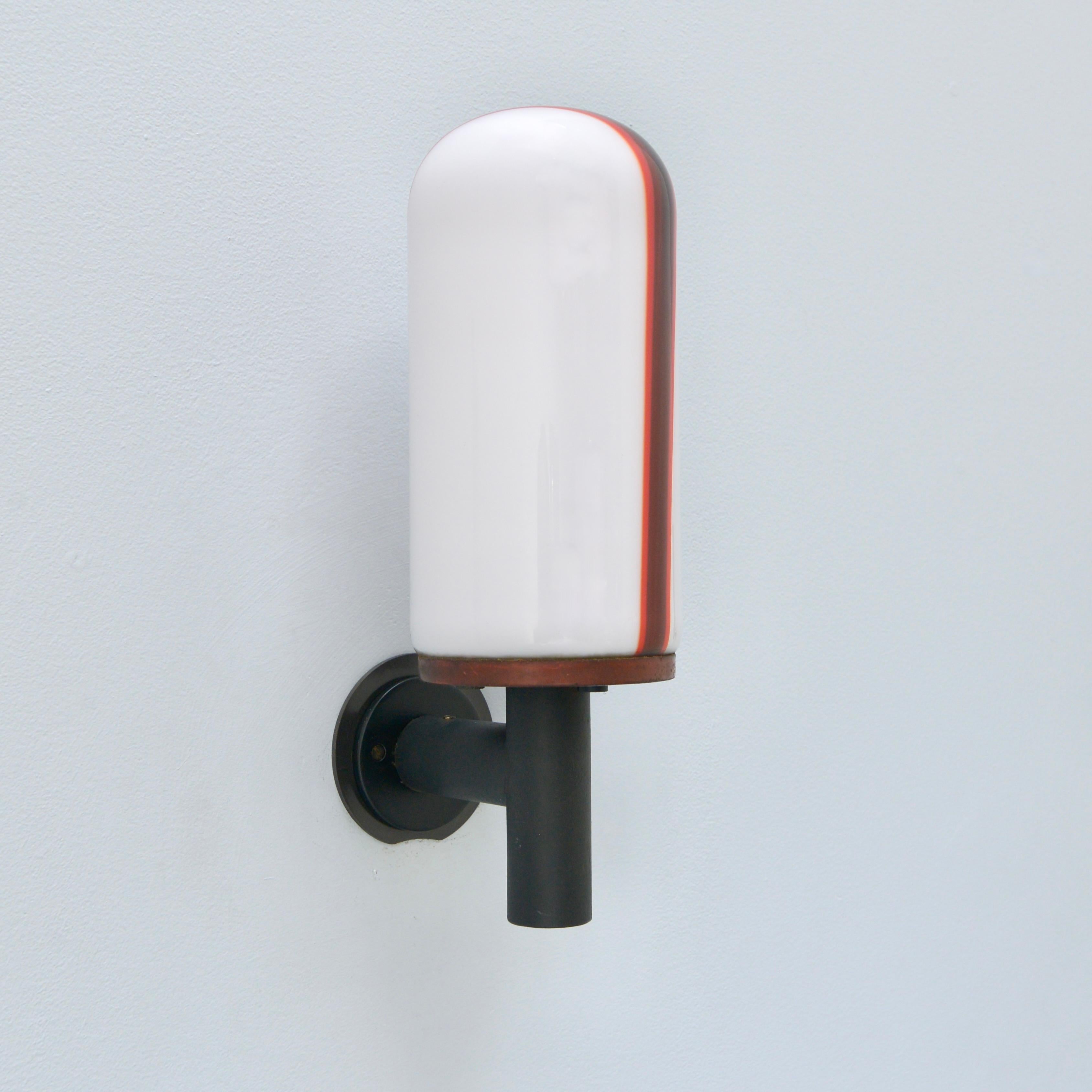 Wonderful 1950s single hand blown Italian exterior sconce by Venini. Soft white glass shade with a red and brown stripe with steel and brass hardware. Partially restored. 1 E26 medium based socket for use in the USA. It can also be wired for use