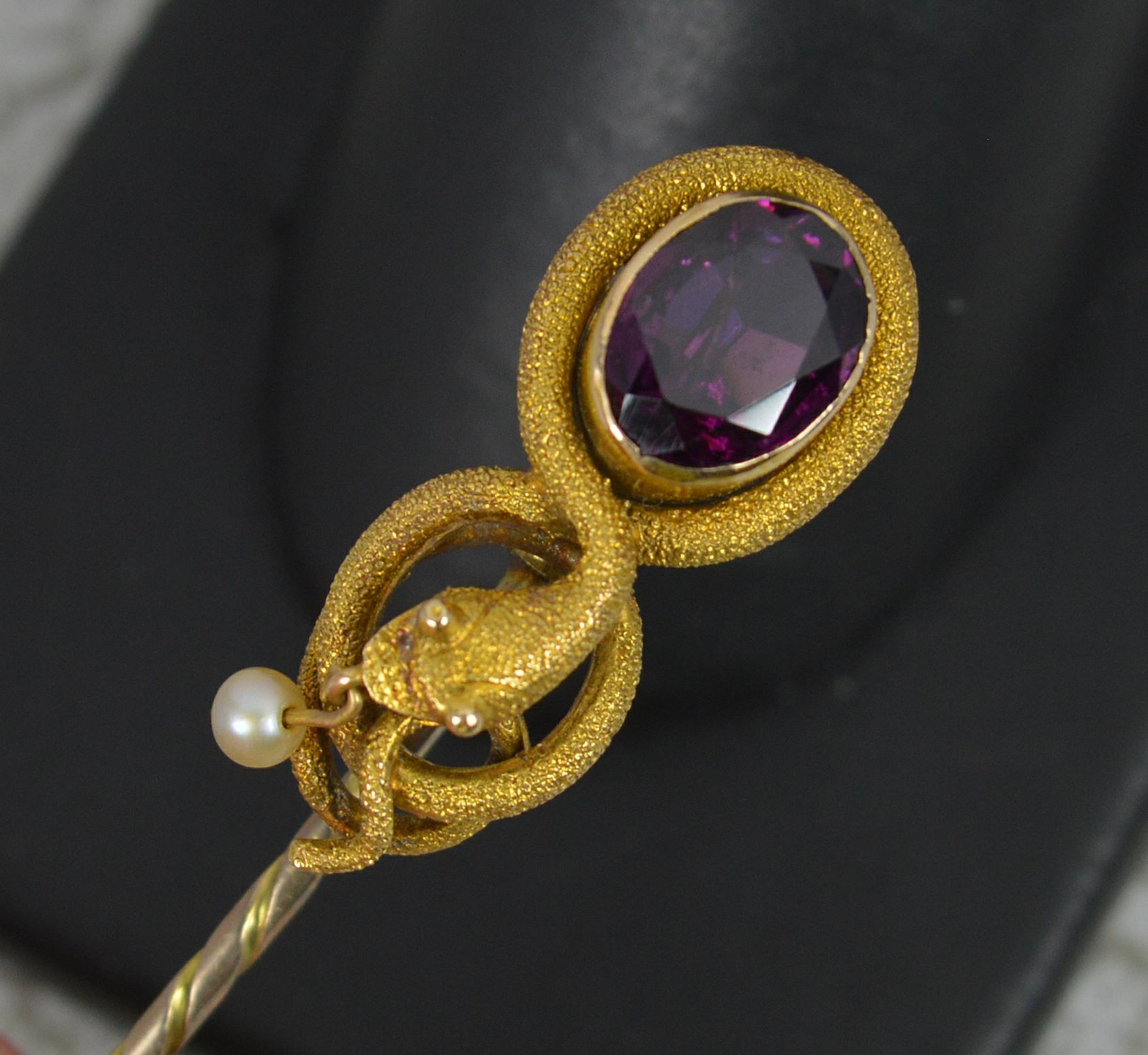 A superb mid Victorian period stick tie pin.
Designed with a snake to top with oval garnet and a pearl dangling below.
15 carat yellow gold head and 9 carat rose gold pin.

CONDITION ; Good for age. Crisp design. Well set, clean stones. Solder marks