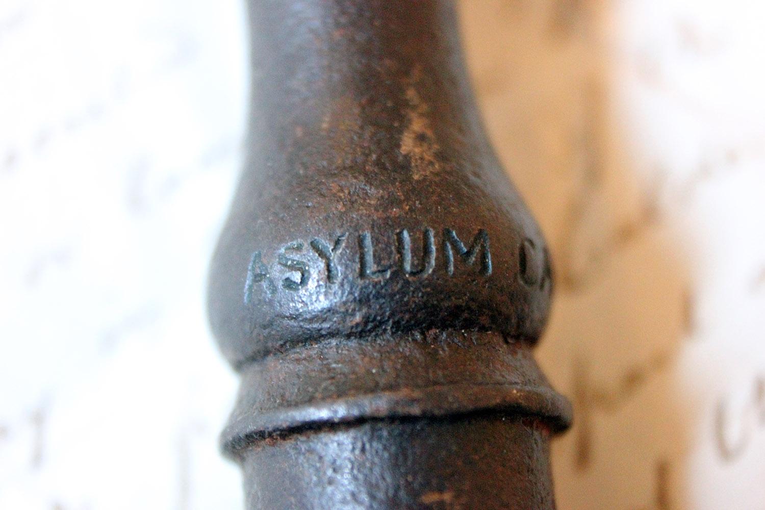 The heavy Victorian period part-barrel shafted iron key having an oval symmetrical bow, the bit with a large cut out, the shank with moulded waisted ripple sections, being marked ‘Asylum Cage Only’ to the shank, complete with weighted black leather