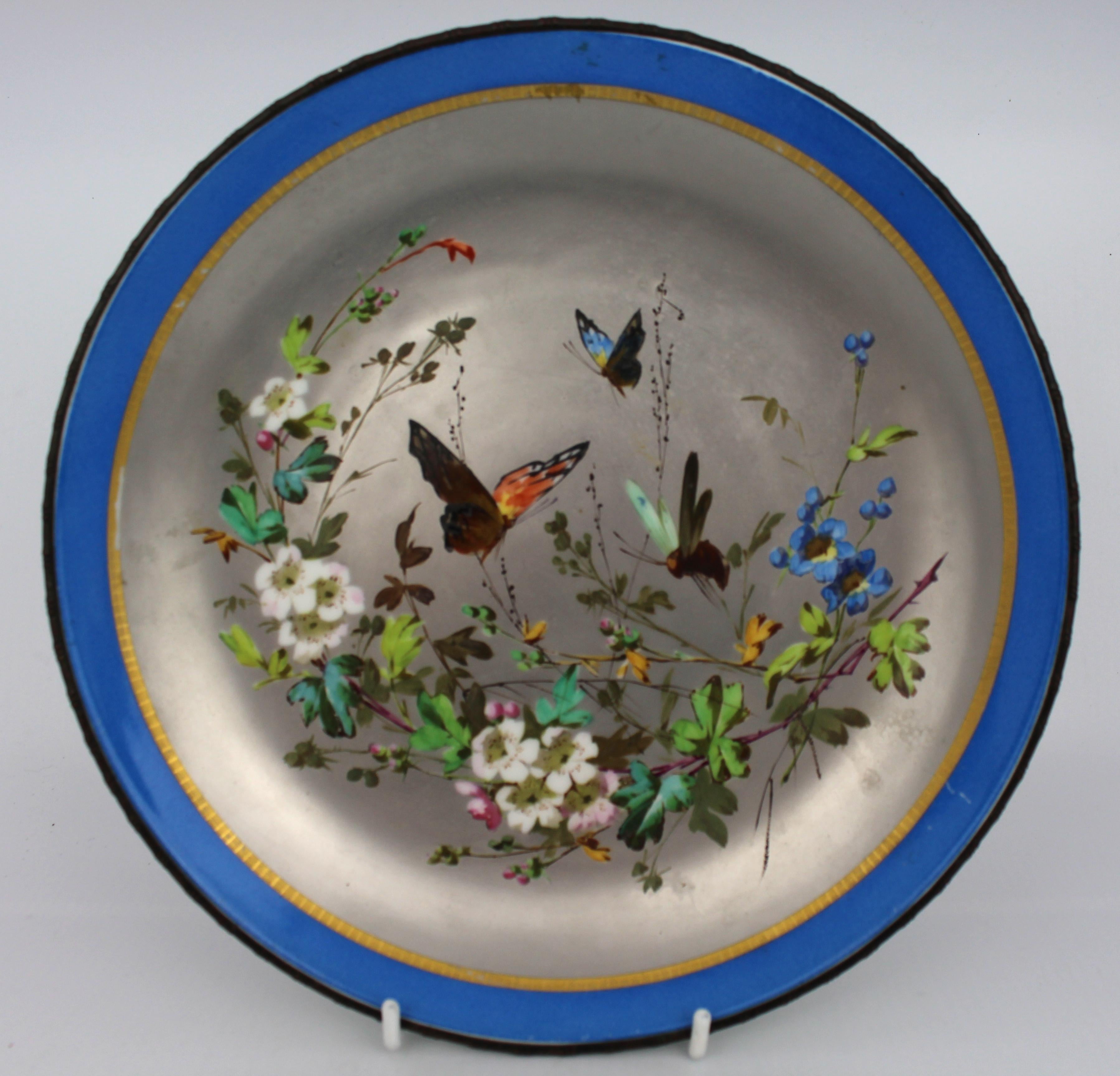 A rare and decorative Victorian porcelain charger, attributed to Minton, England, circa 1875–1890. The central field is exquisitely hand-painted with butterflies, a dragonfly, and floral sprays in vibrant enamel, all set against a softly lustrous